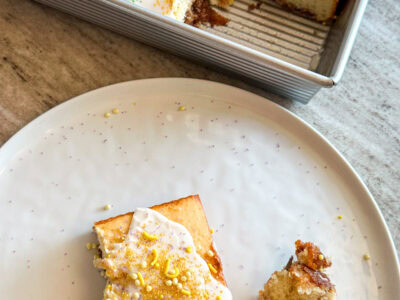 A white plate with a slice of king cake with the cake pan in the background with the king cake inspired sheet cake.