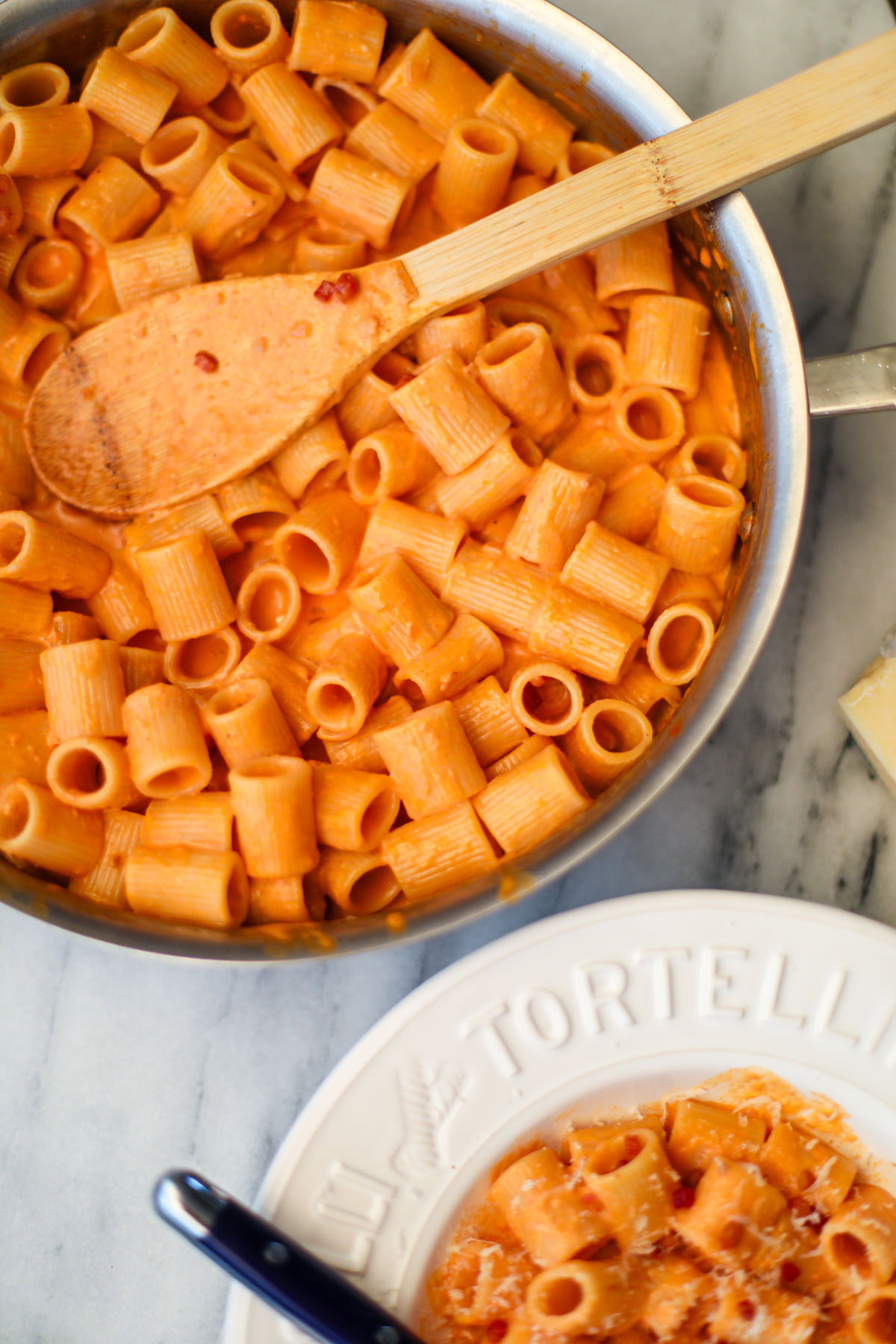 A stainless steel skillet of blush sauce with a wooden spoon.