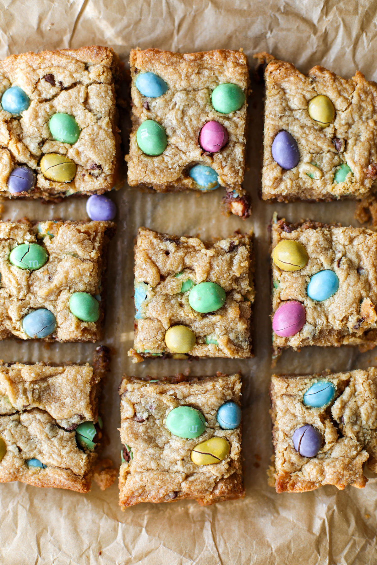 A baking pan of Easter blondies on a marble counter with loose m&m eggs spread around the counter.