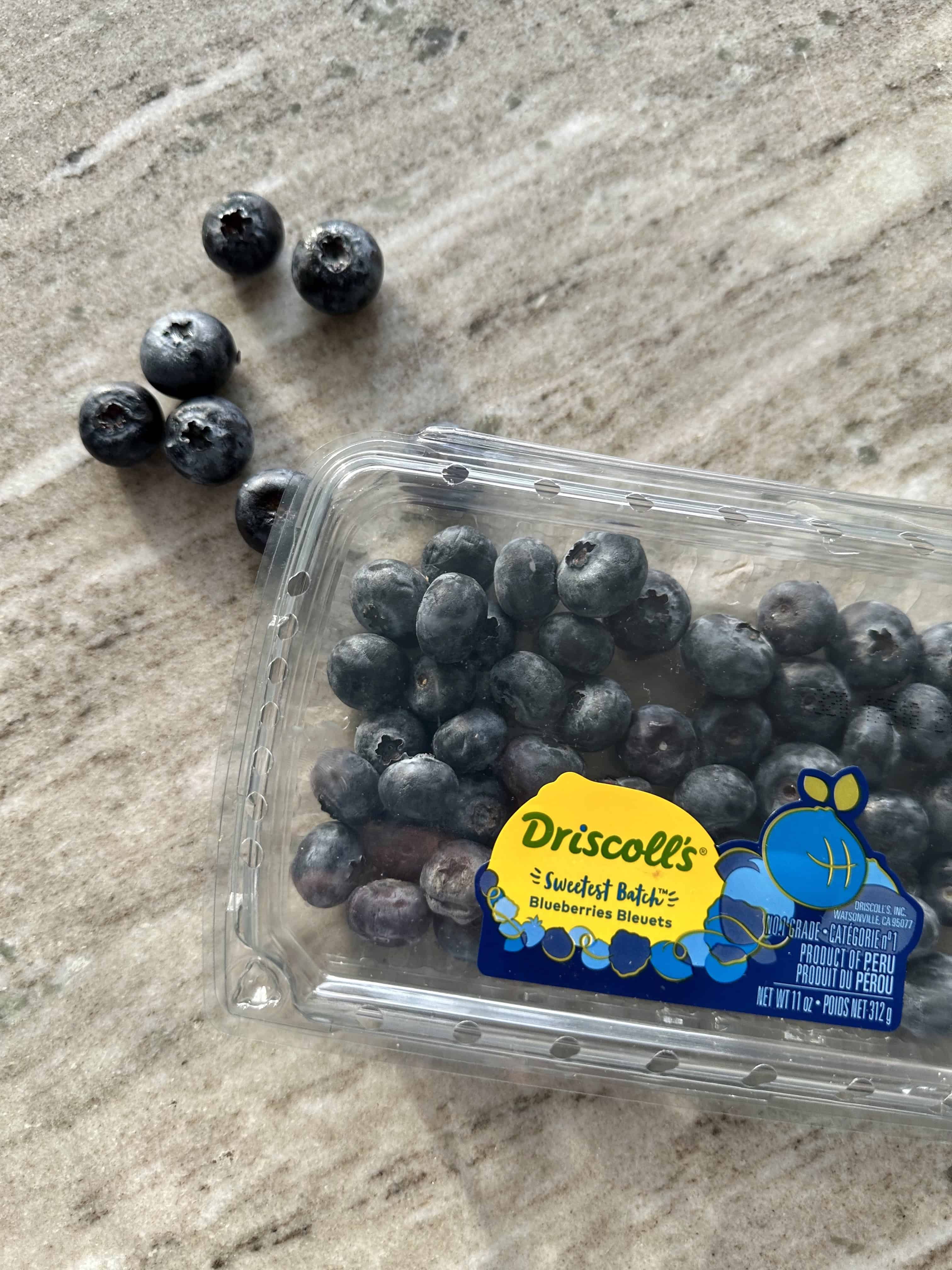 A gray countertop with a carton of blueberries.
