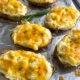 A sheet pan lined with foil with twice baked potatoes topped with chopped chives and flaky salt.
