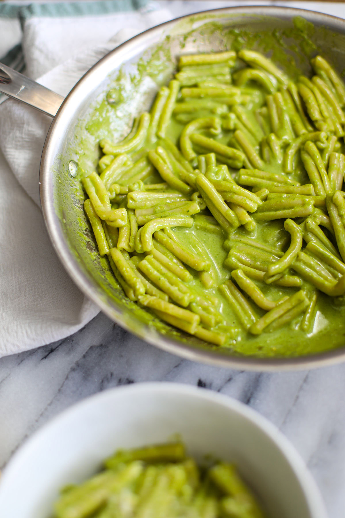 A close up of noodles tossed with creamy pesto pasta. 
