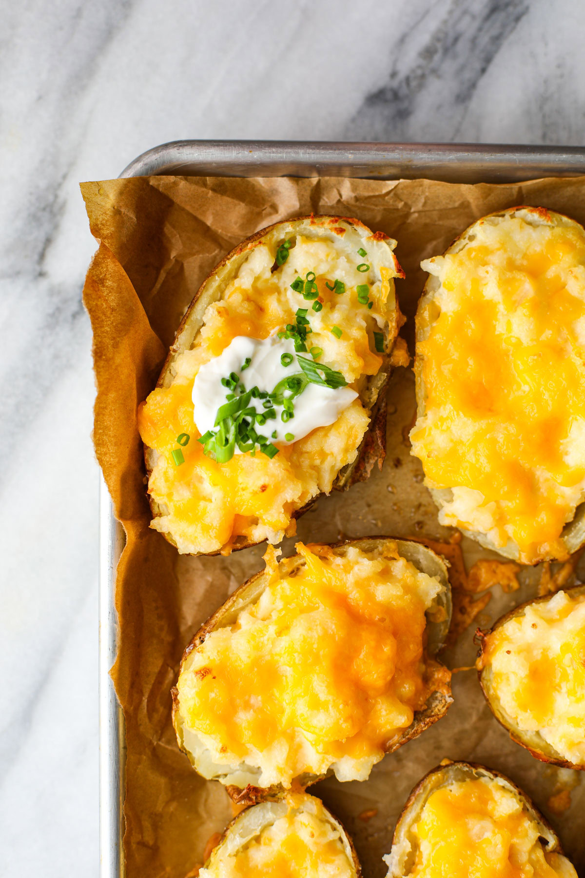 Up close of twice baked potatoes on a parchment lined baking sheet.