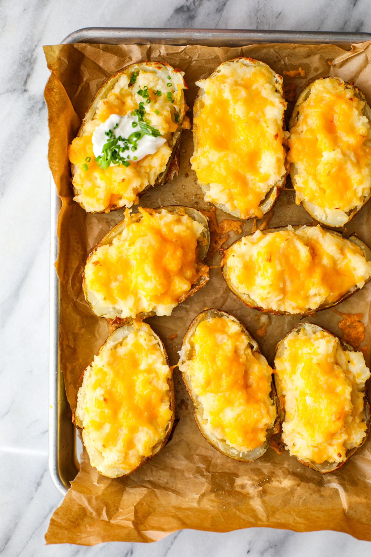 Up close of twice baked potatoes on a parchment lined baking sheet.