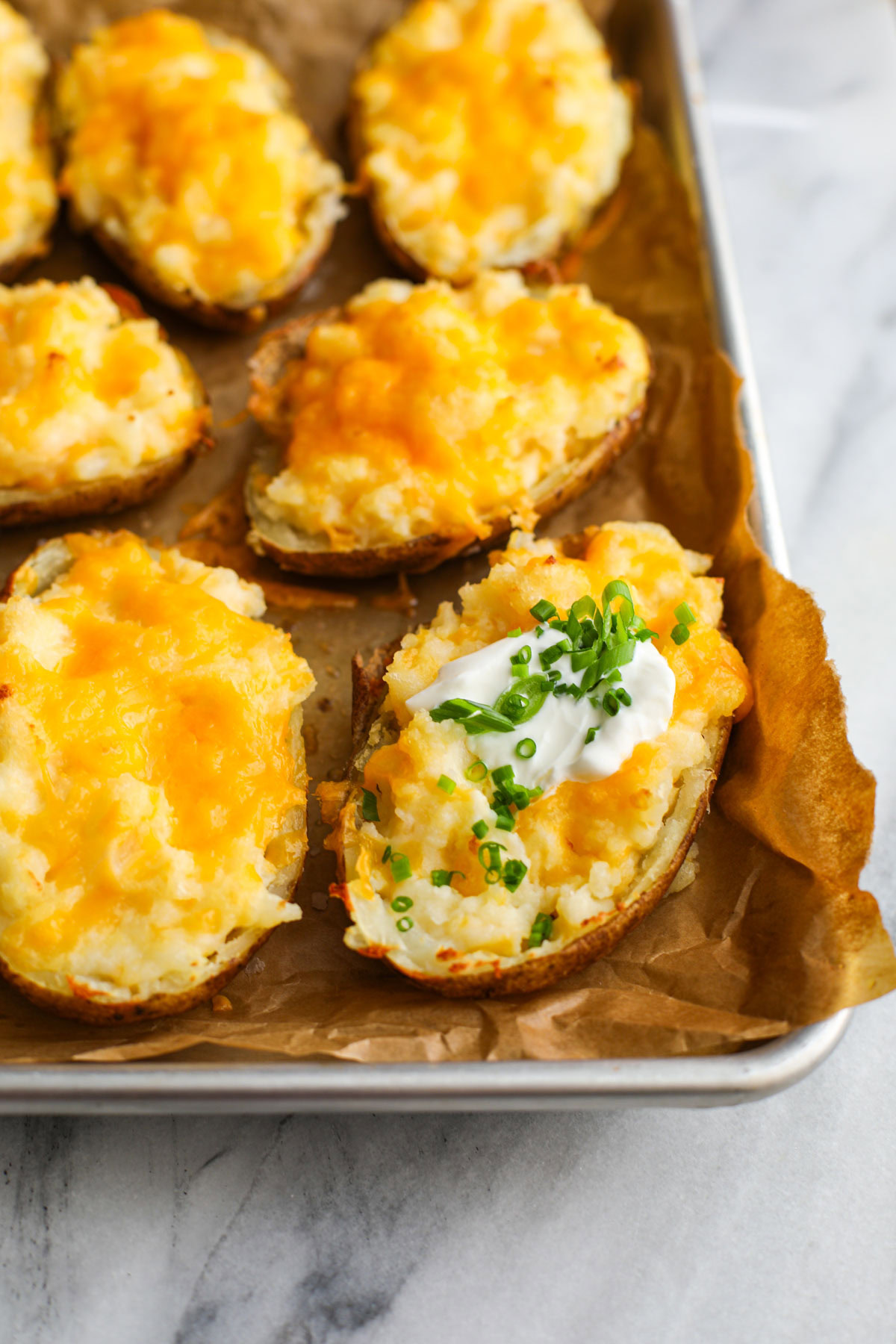 Up close of twice baked potatoes on a parchment lined baking sheet.