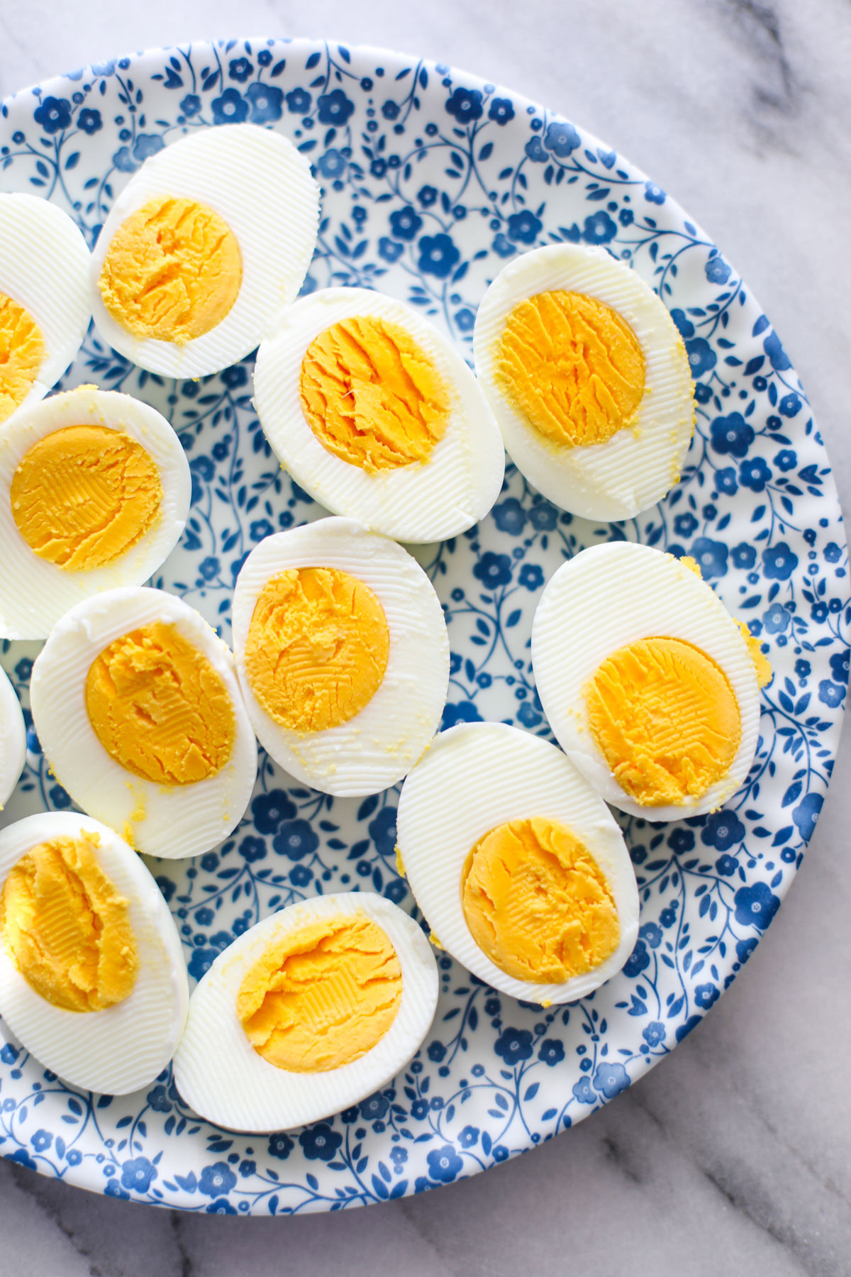 Halved hardboiled eggs on a blue floral plate. 