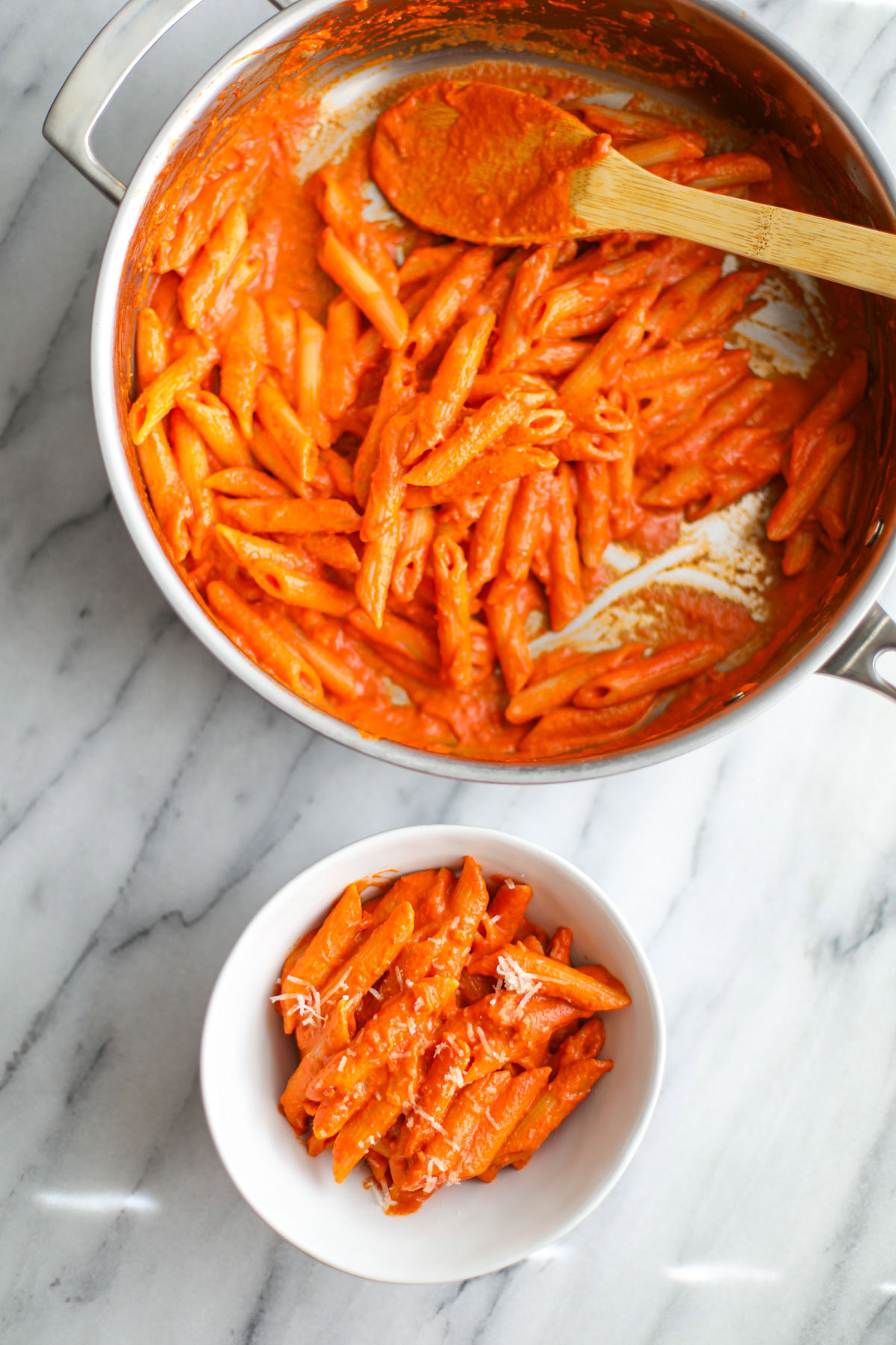 A pan of vodka sauce pasta with a bowl next to it.