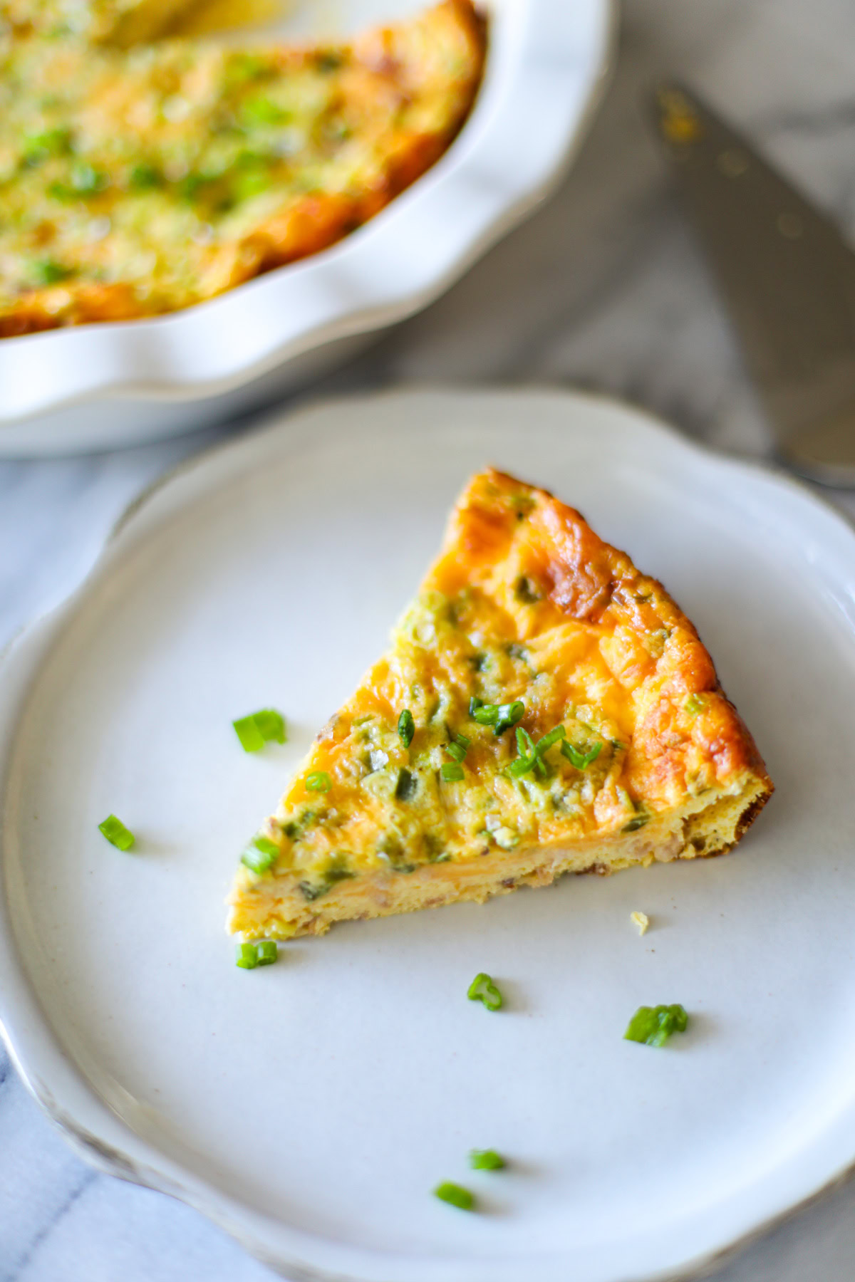 A slice of quiche on a white plate.