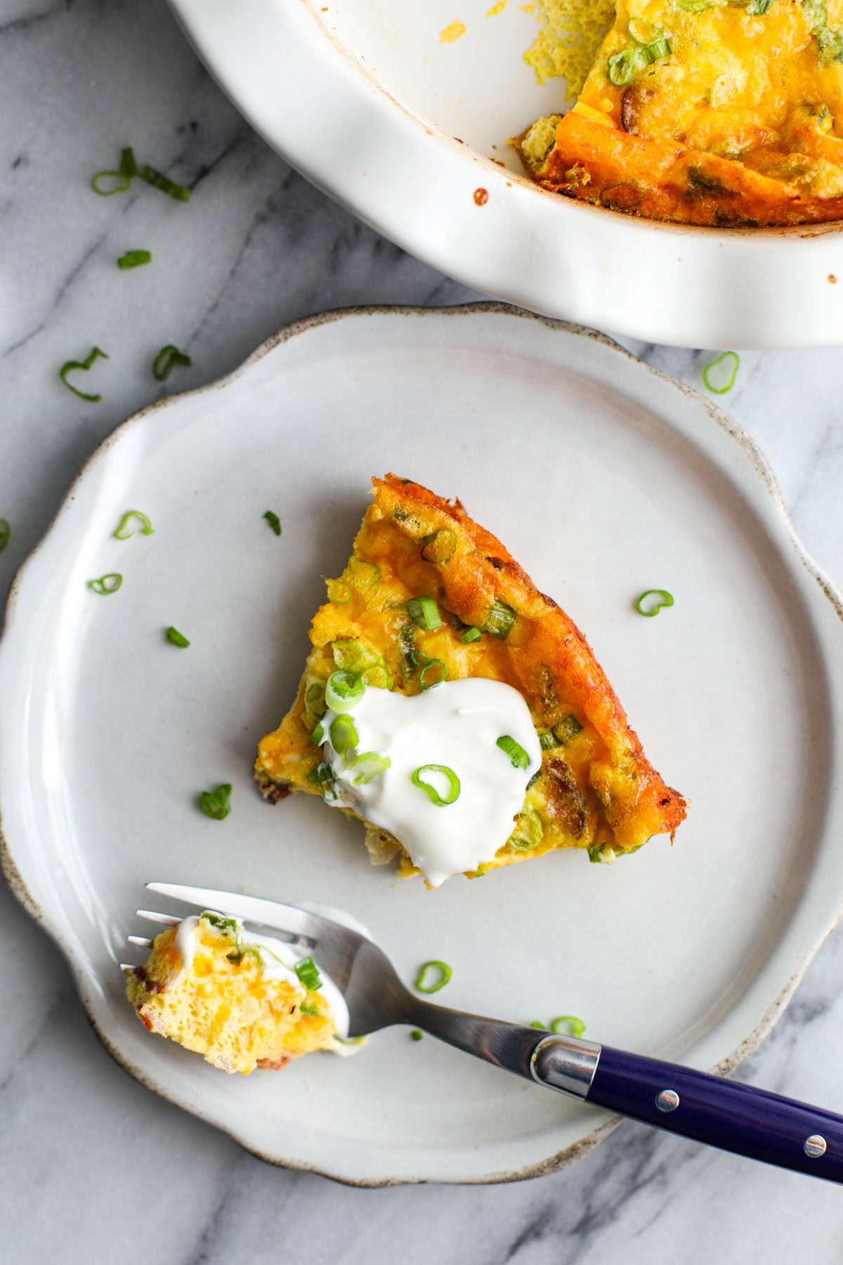 A slice of quiche on a white plate.