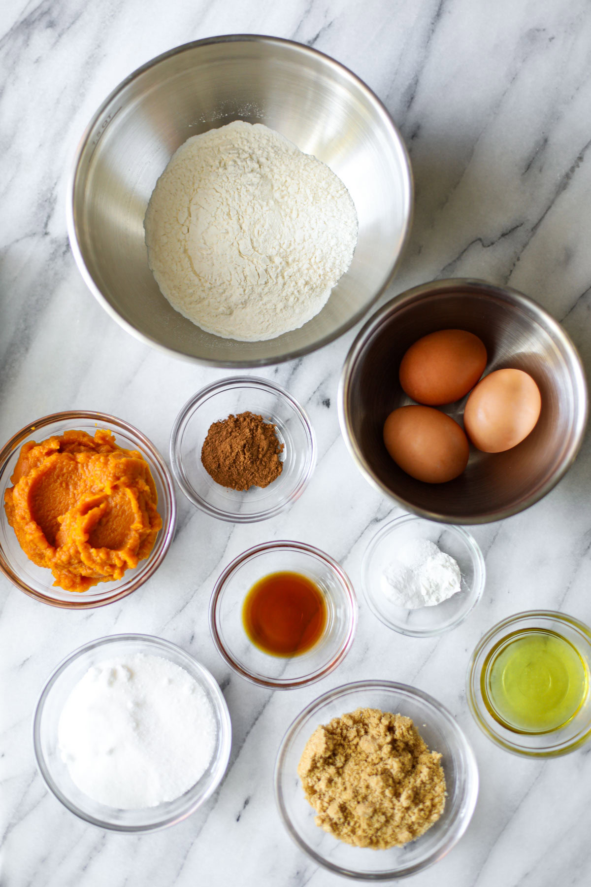 A bowl of flour, eggs, pumpkin, cinnamon, vanilla, baking soda, light brown sugar, egg whites, and white sugar.