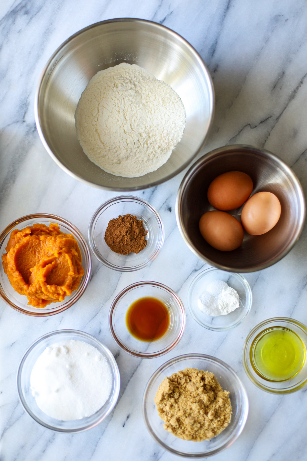 A bowl of flour, eggs, pumpkin, cinnamon, vanilla, baking soda, light brown sugar, egg whites, and white sugar.