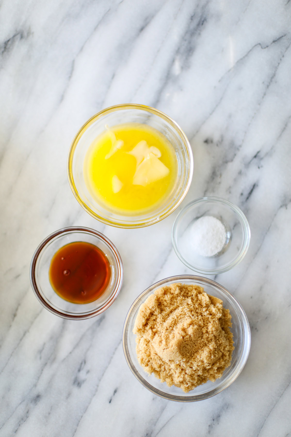 Clear bowls filled with sticky bun topping including melted butter, salt, honey, and light brown sugar.