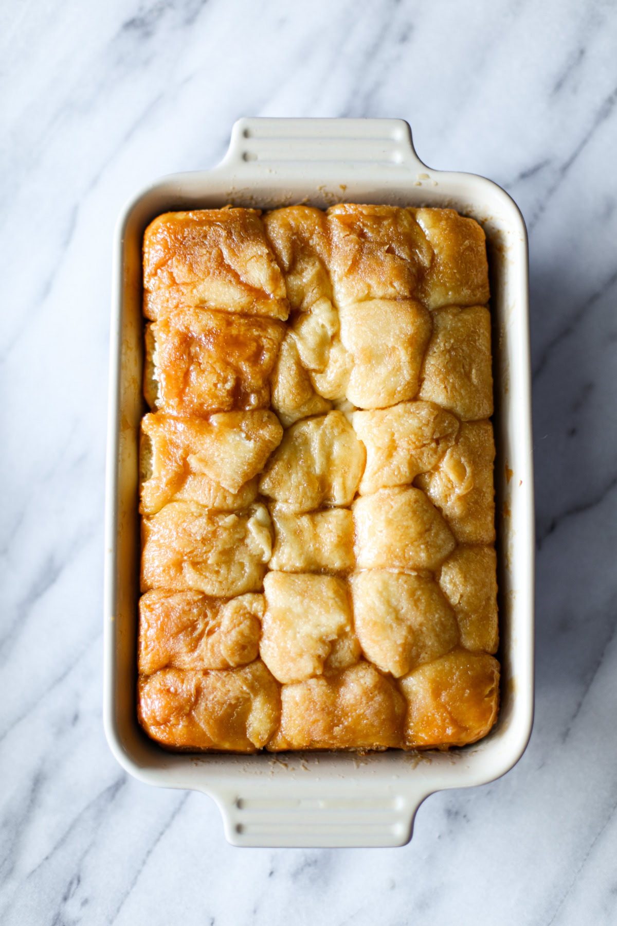 A rectangular blue baking dish of golden brown sticky buns.