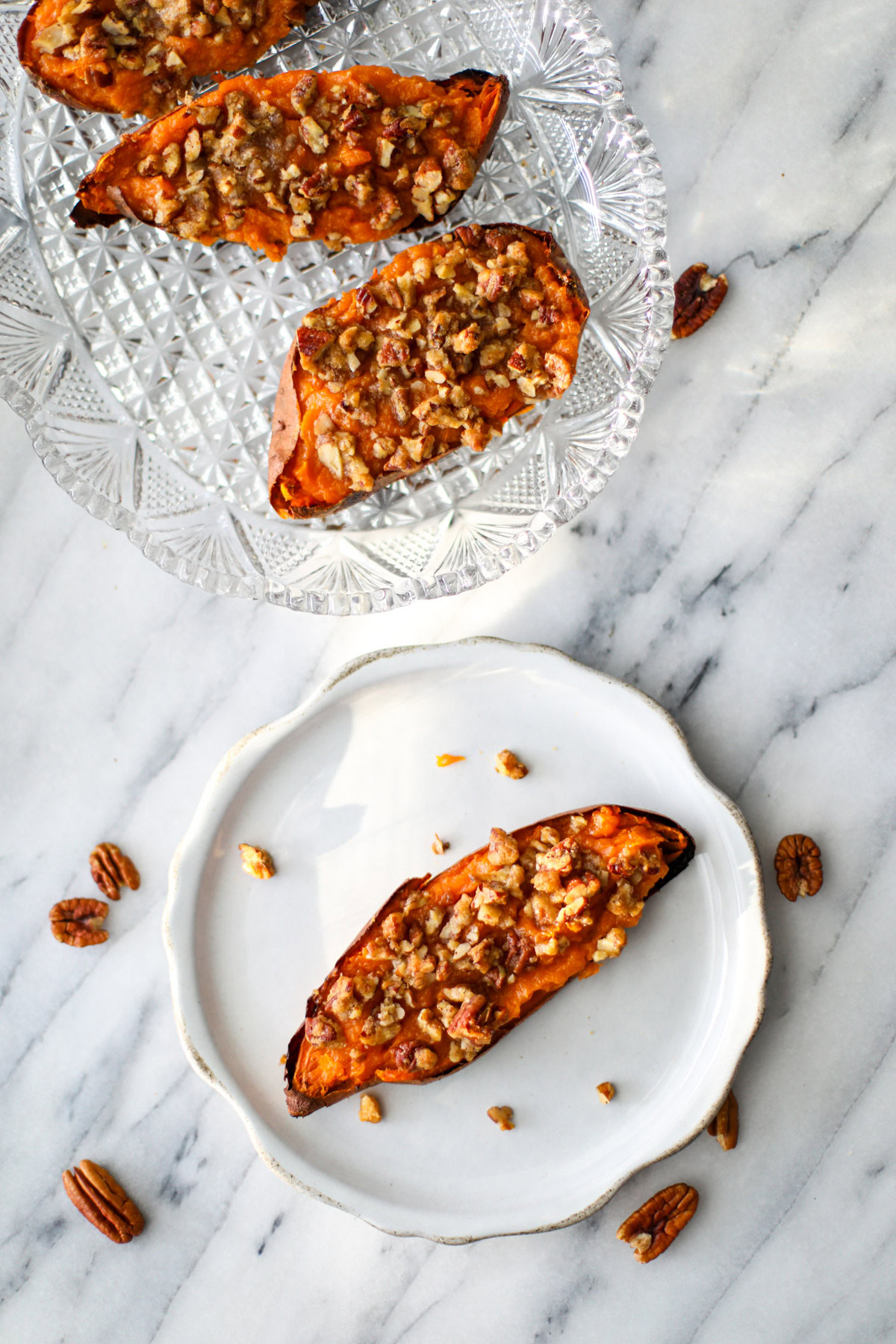 A twice baked sweet potato on a white plate with a clear dish of several more in the background.