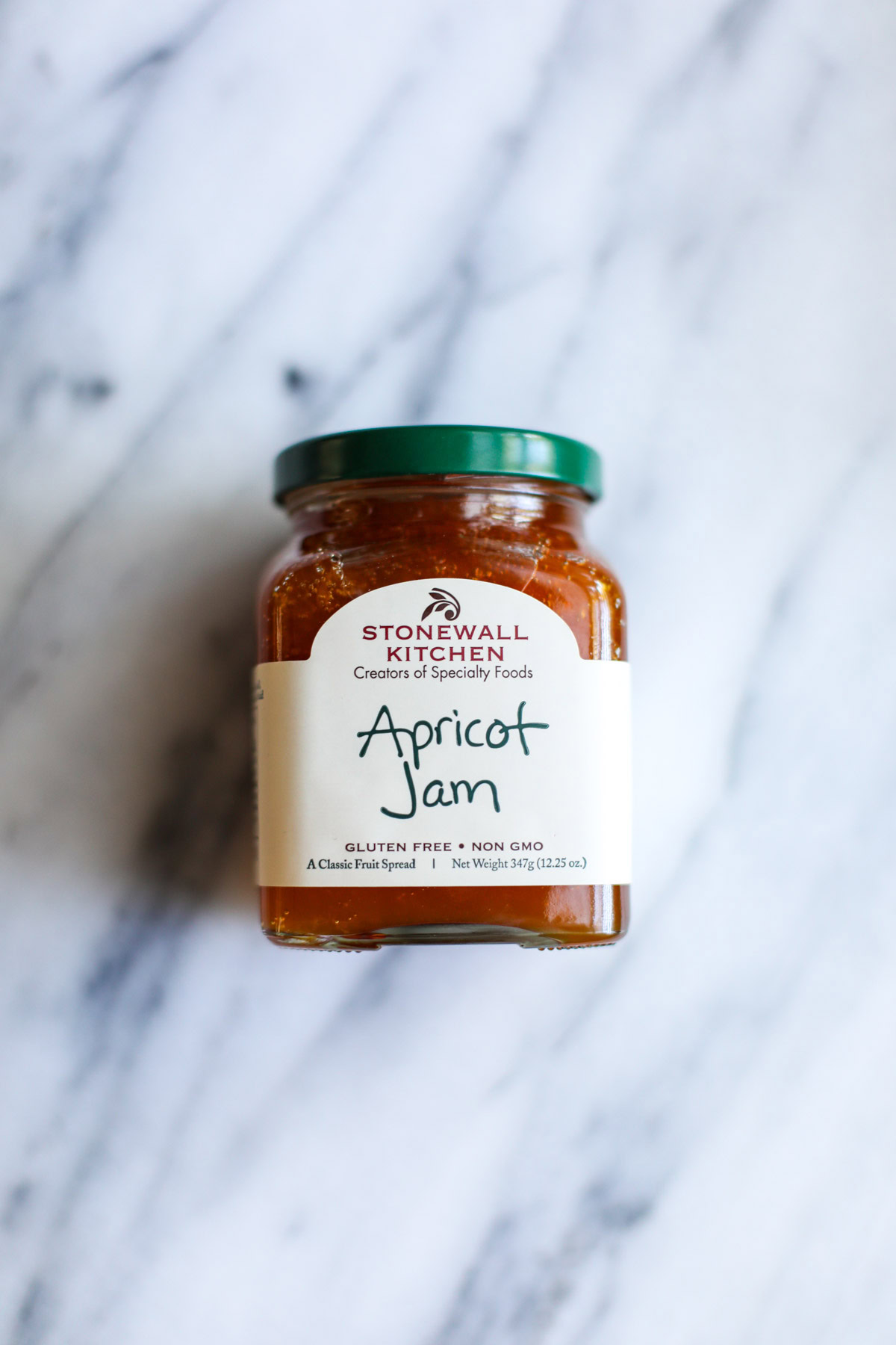 A jar of stonewall kitchen apricot jam on a marble counter.