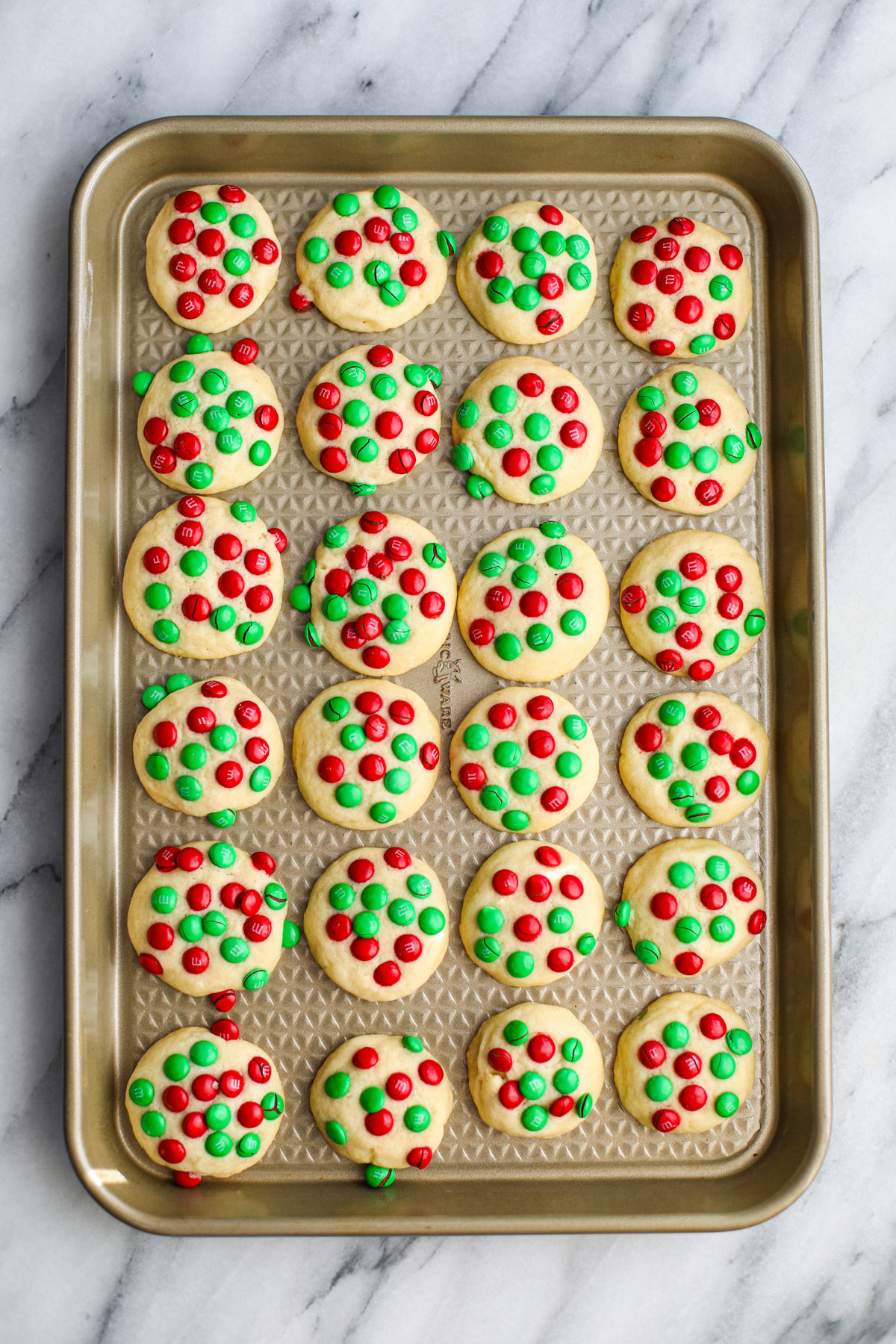 A gold sheet tray of red and green Christmas Mini M&M butter cookies.