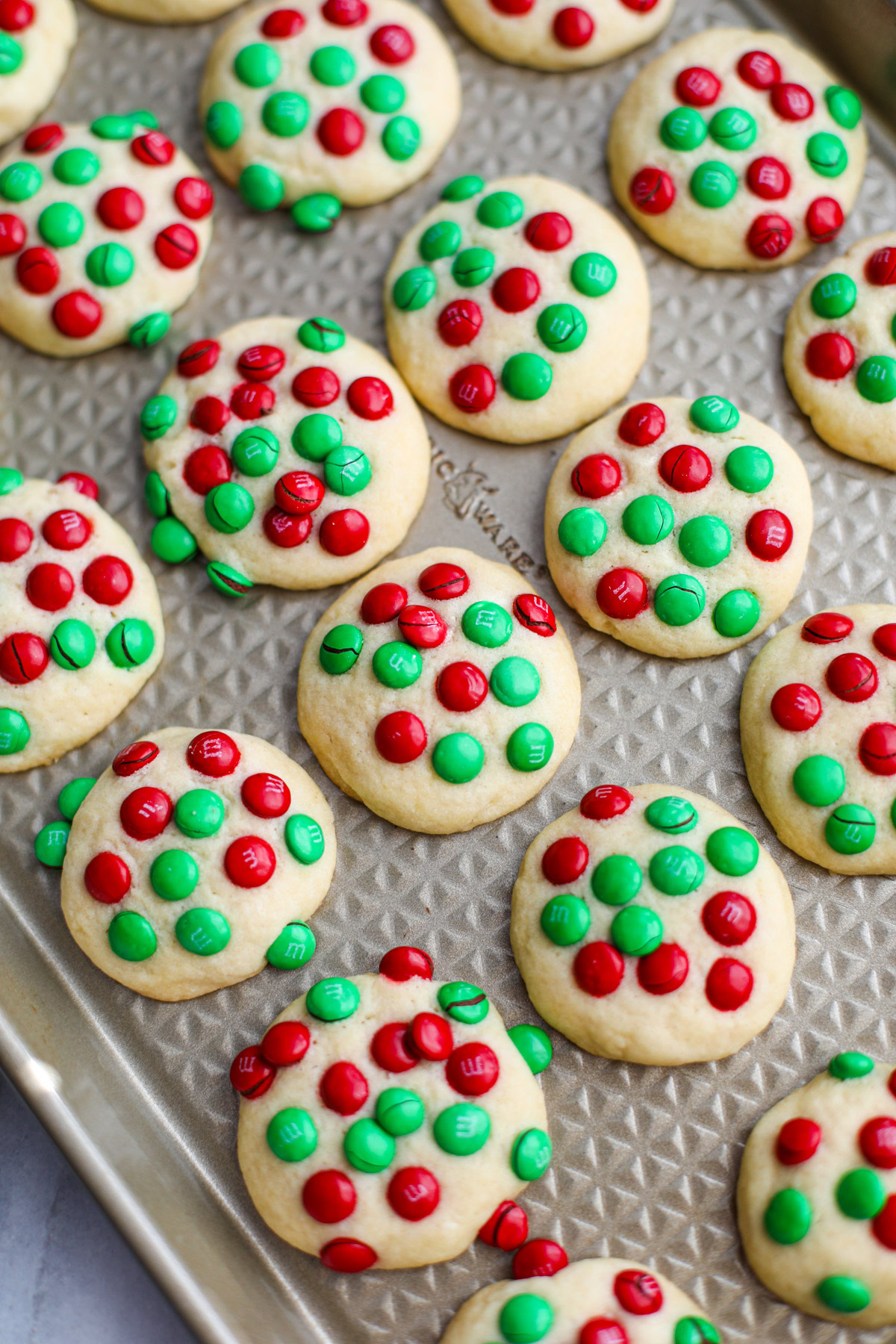 A gold sheet tray of red and green Christmas Mini M&M butter cookies.