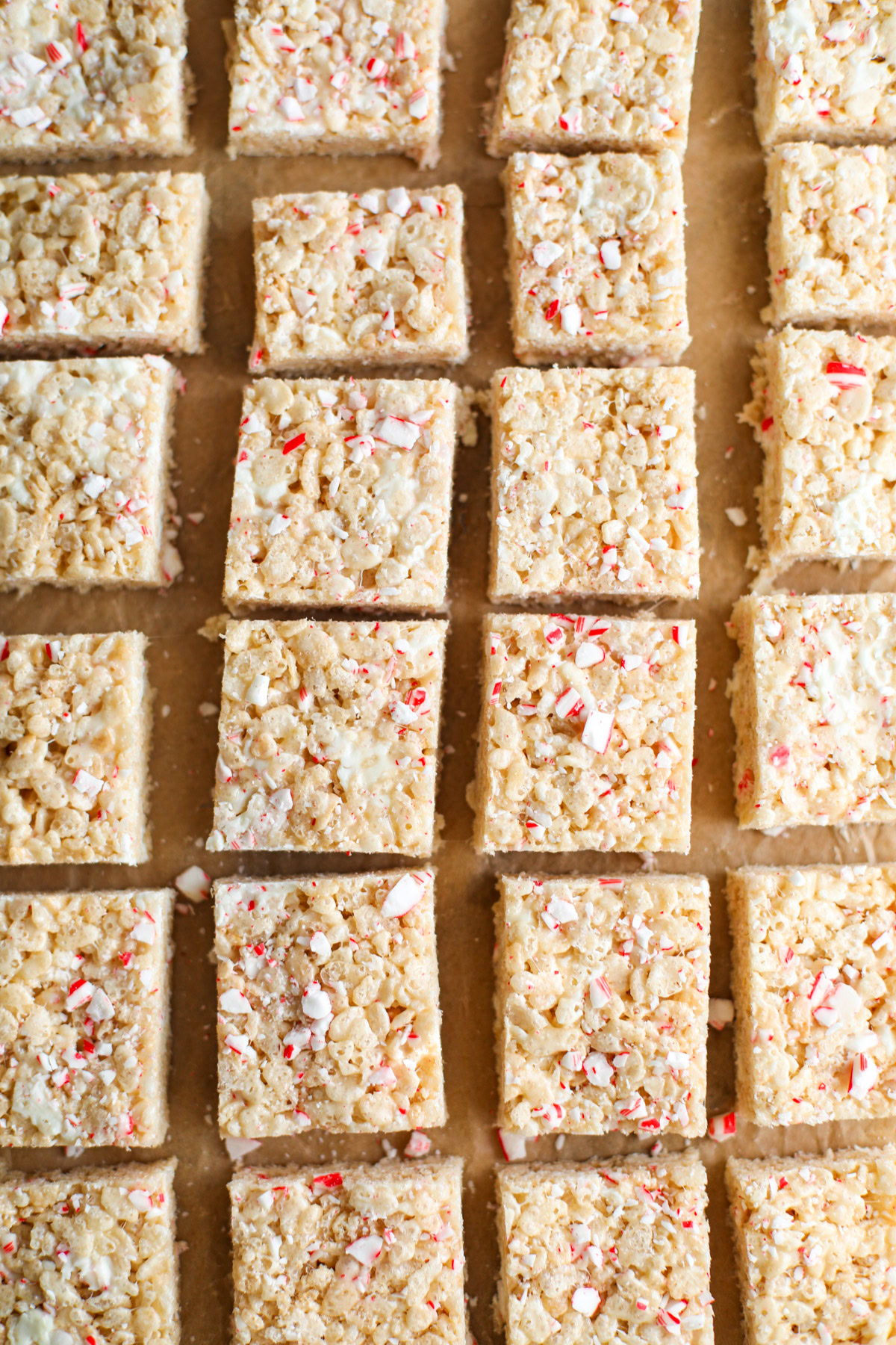 Rows of red and white Rice Krispie treats on brown parchment paper.