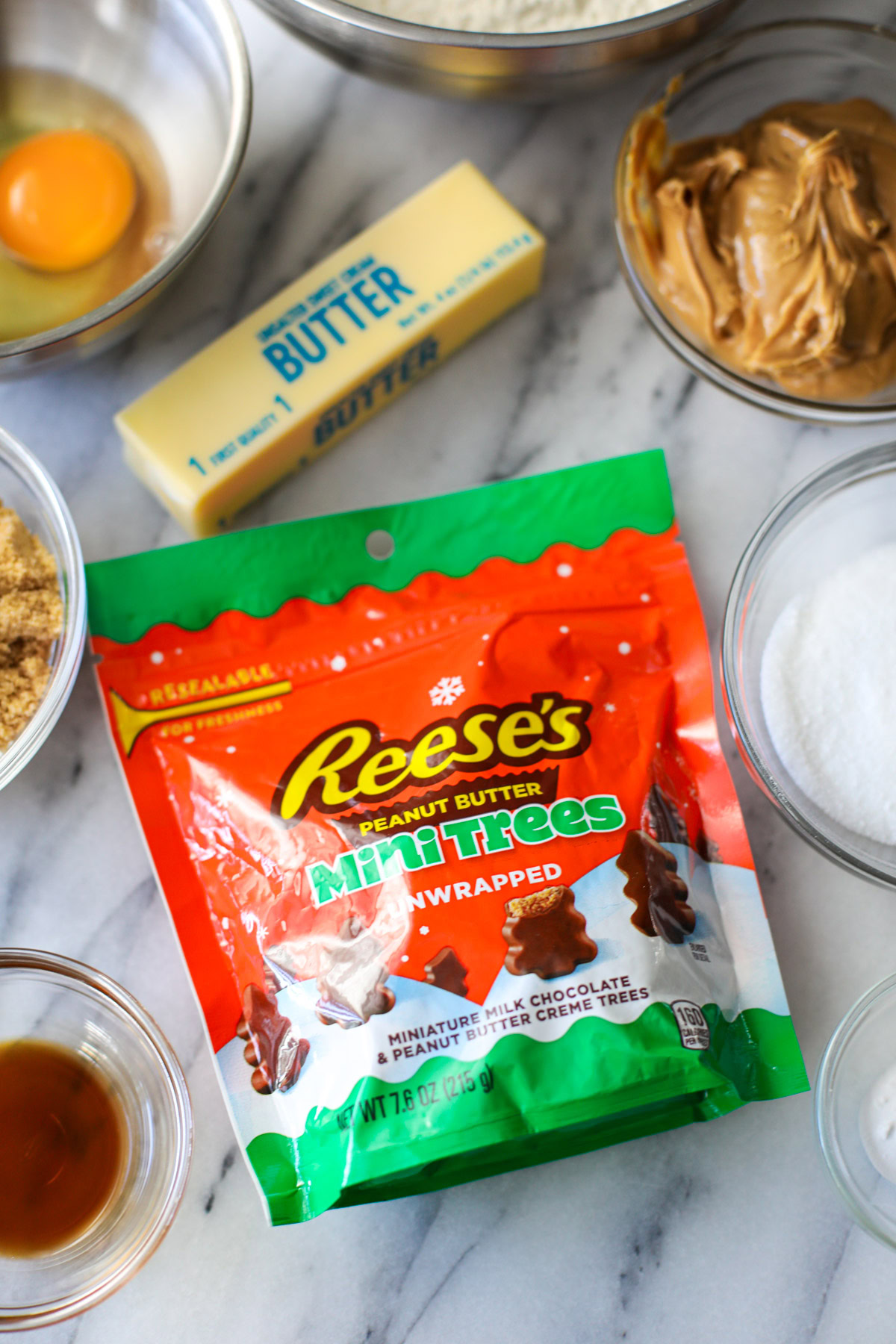 A bag of Reese's Mini Peanut Butter Trees surrounded by glass bowls of ingredients. 
