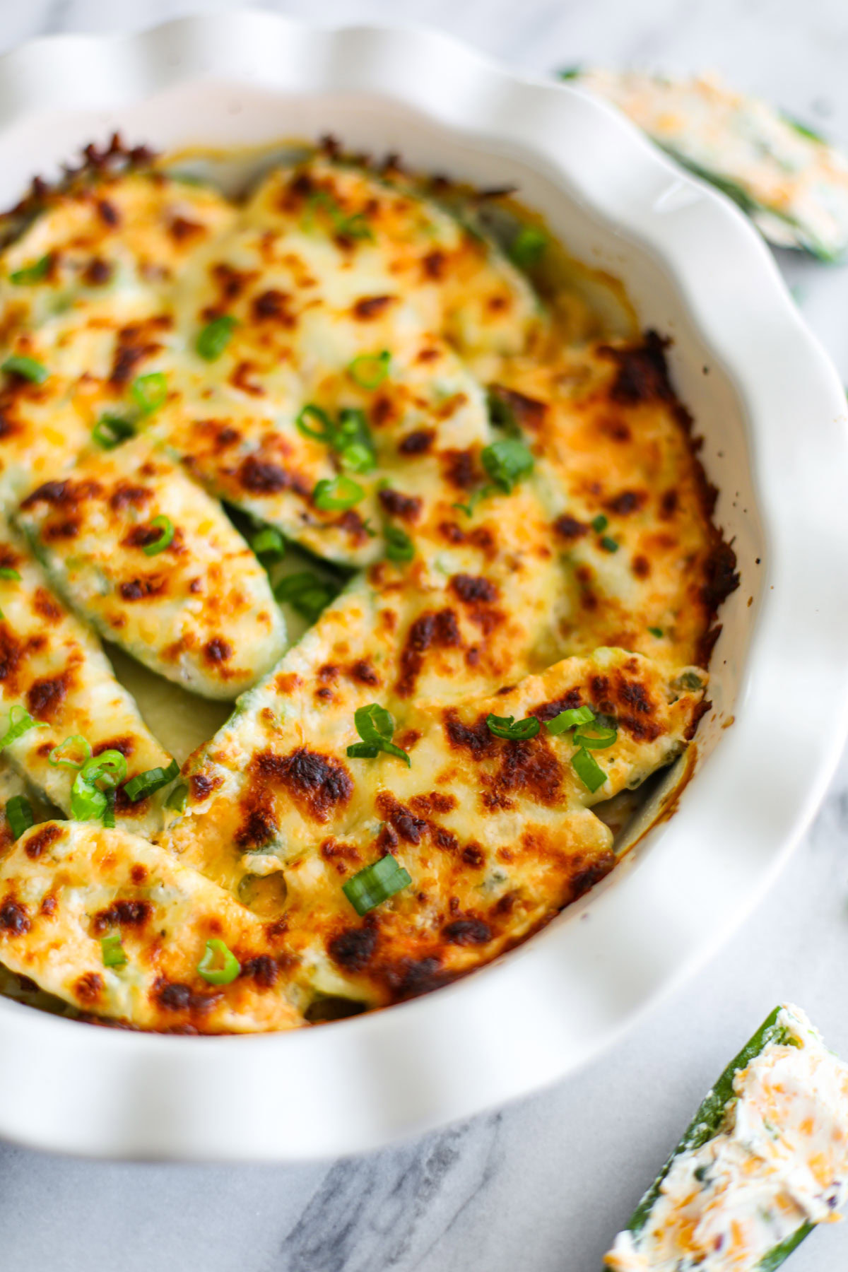 A close up of golden jalapeño poppers topped with slices of green onions.