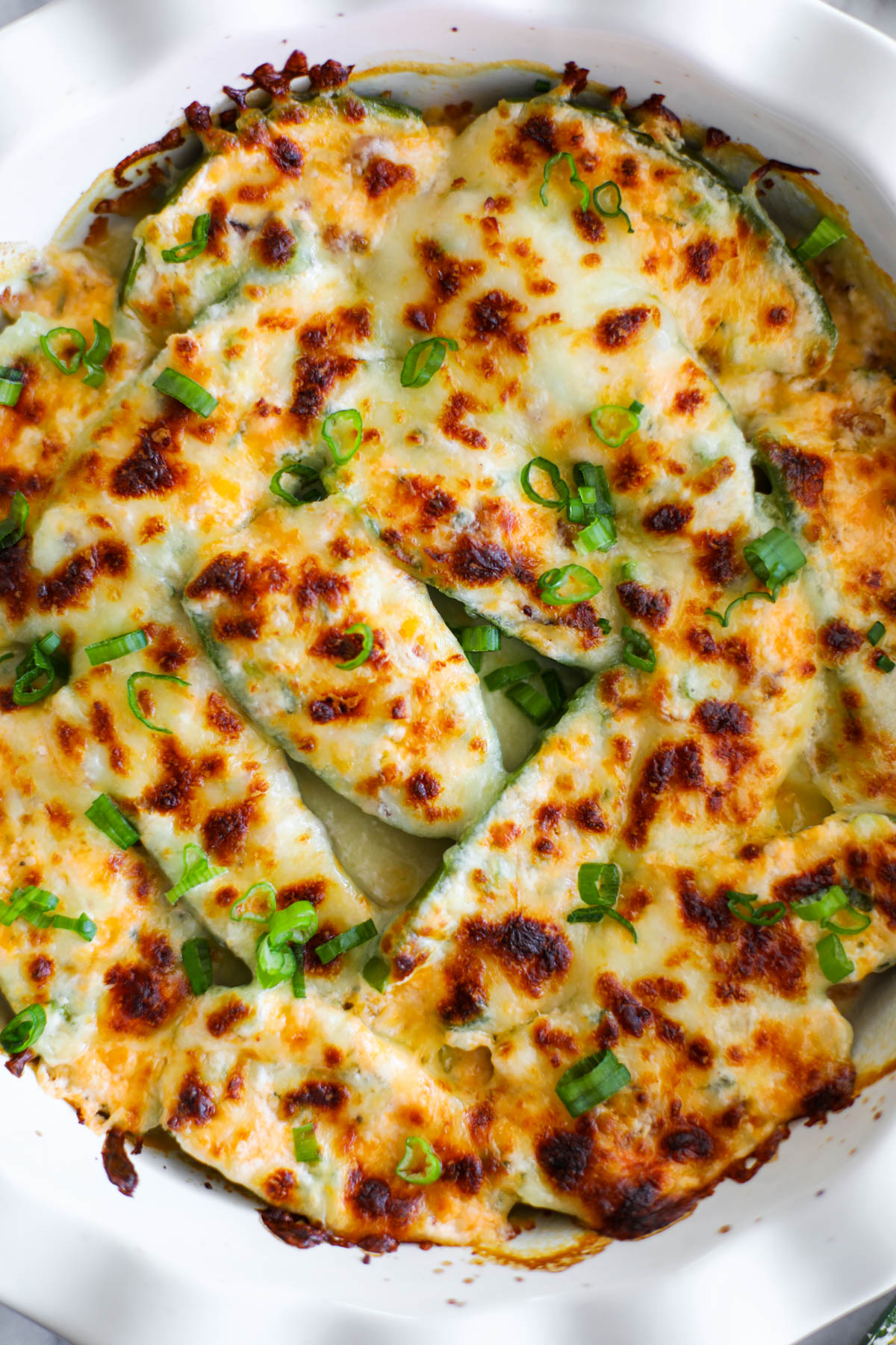 A close up of golden jalapeño poppers topped with slices of green onions.