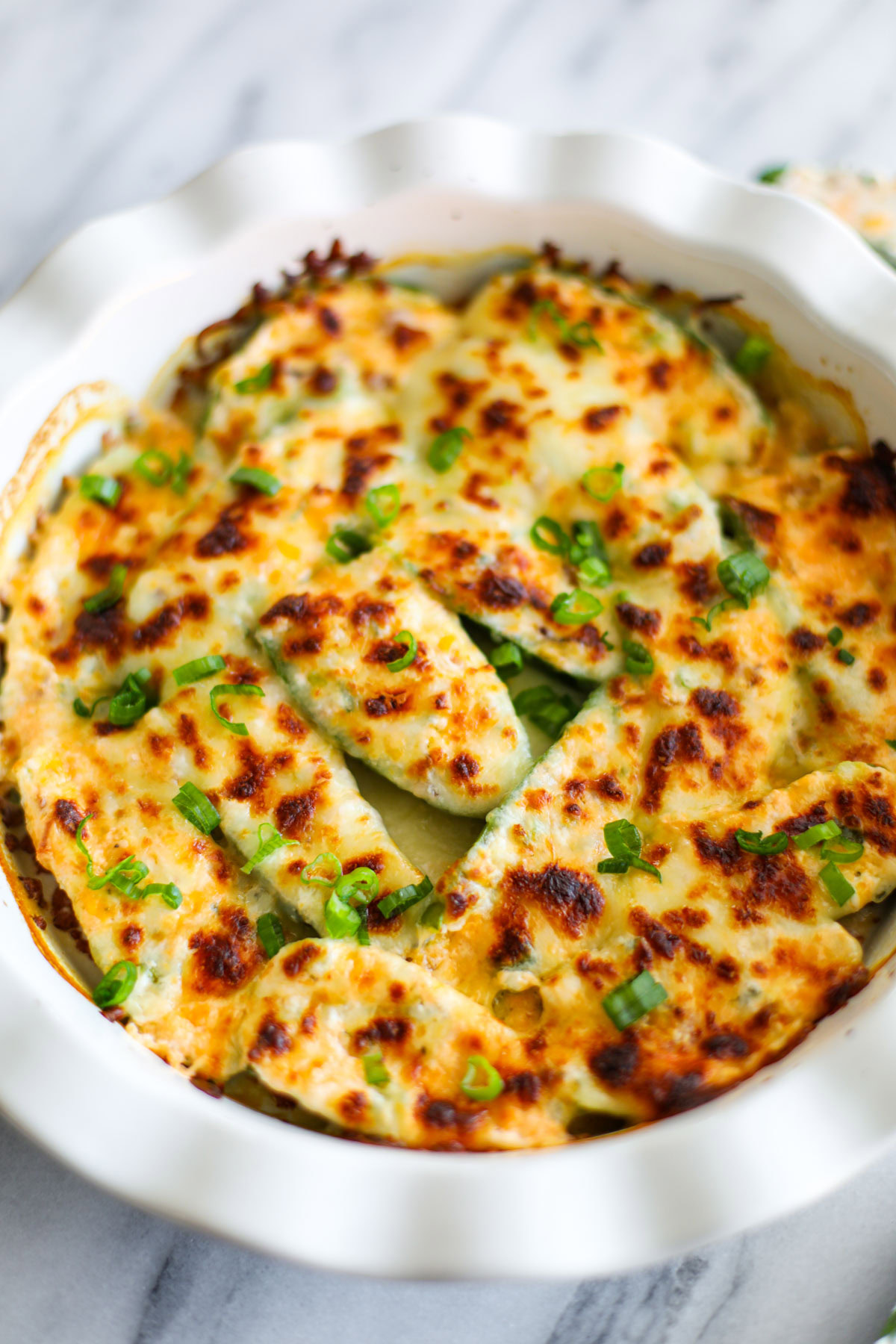 A close up of golden jalapeño poppers topped with slices of green onions.