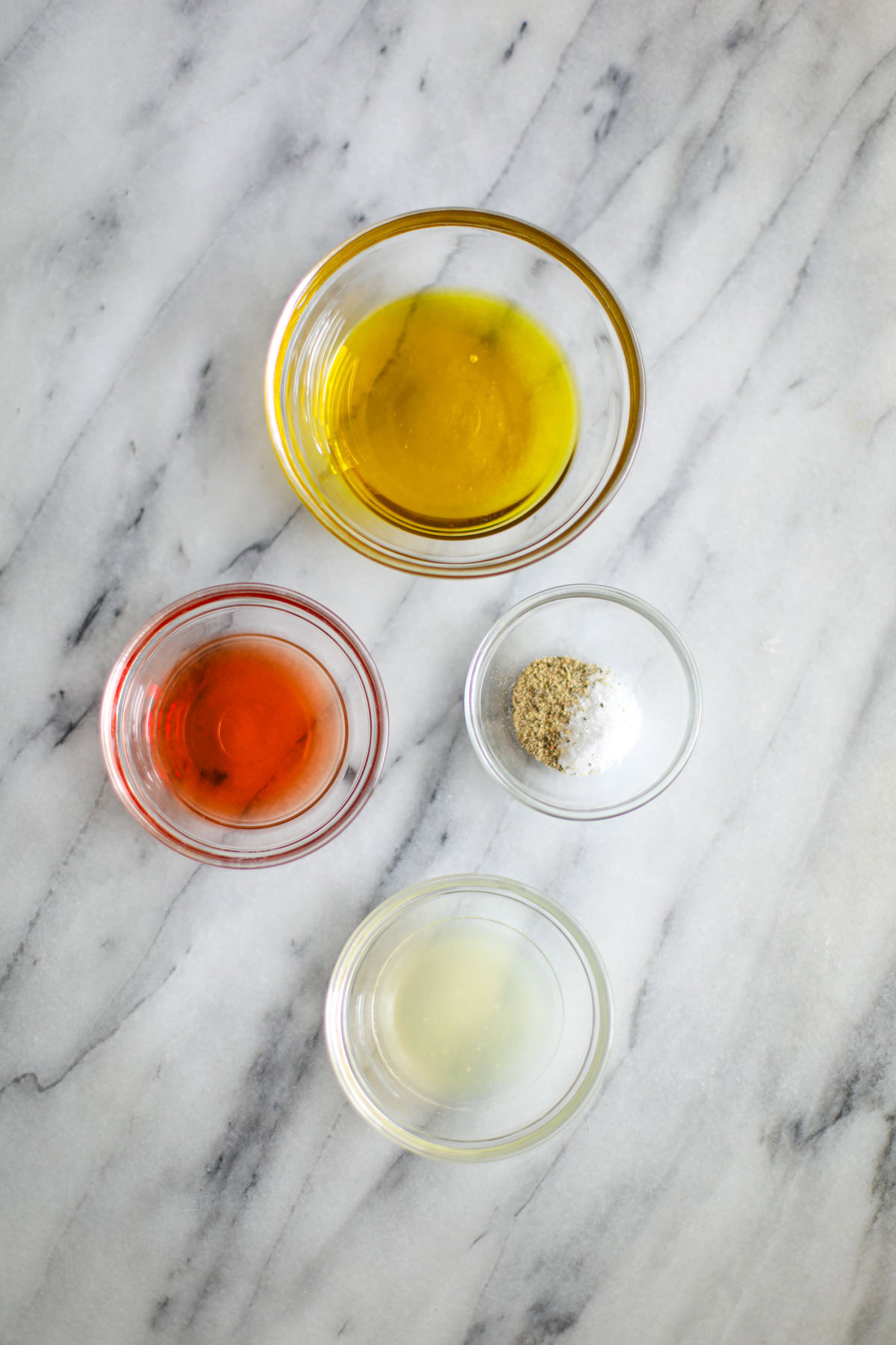 Glass bowls of vinegar, oil, seasonings, and lemon juice. 
