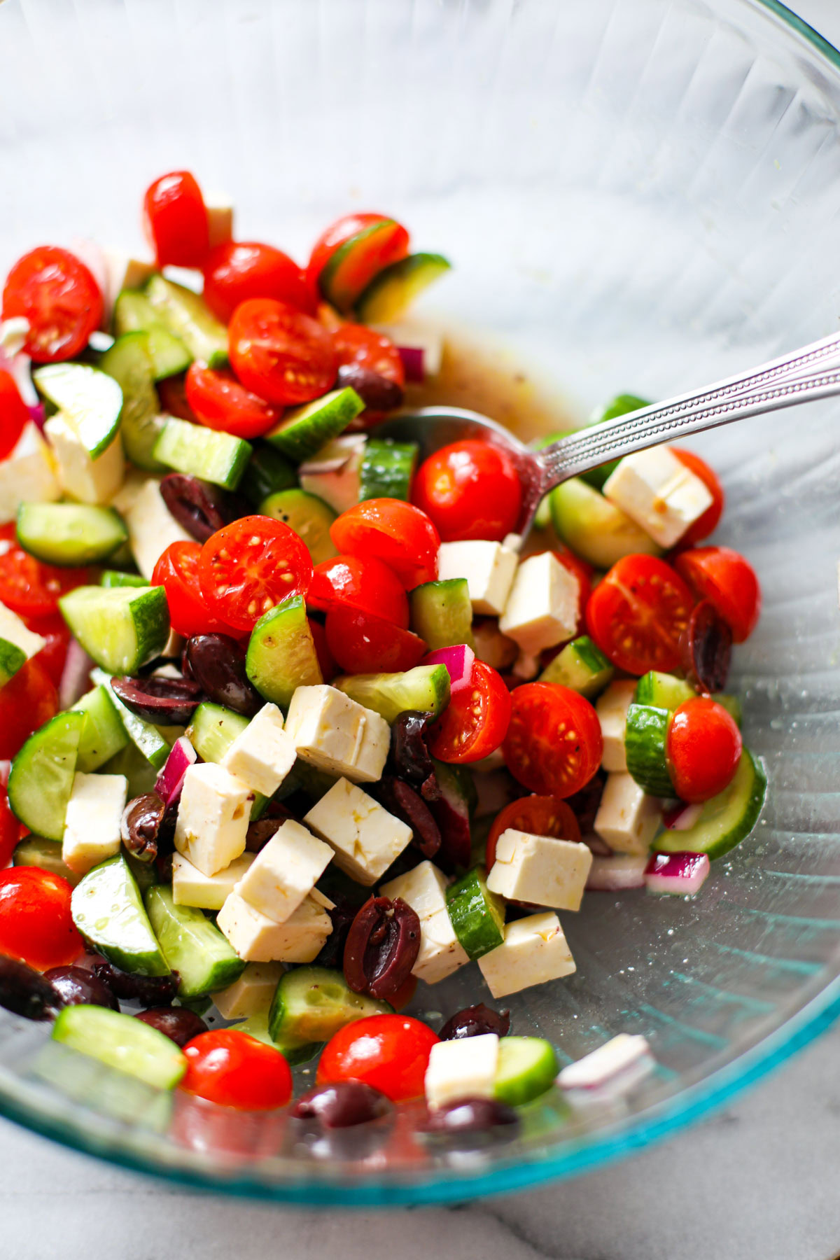 Cucumber tomato feta salad in a large glass mixing bowl.