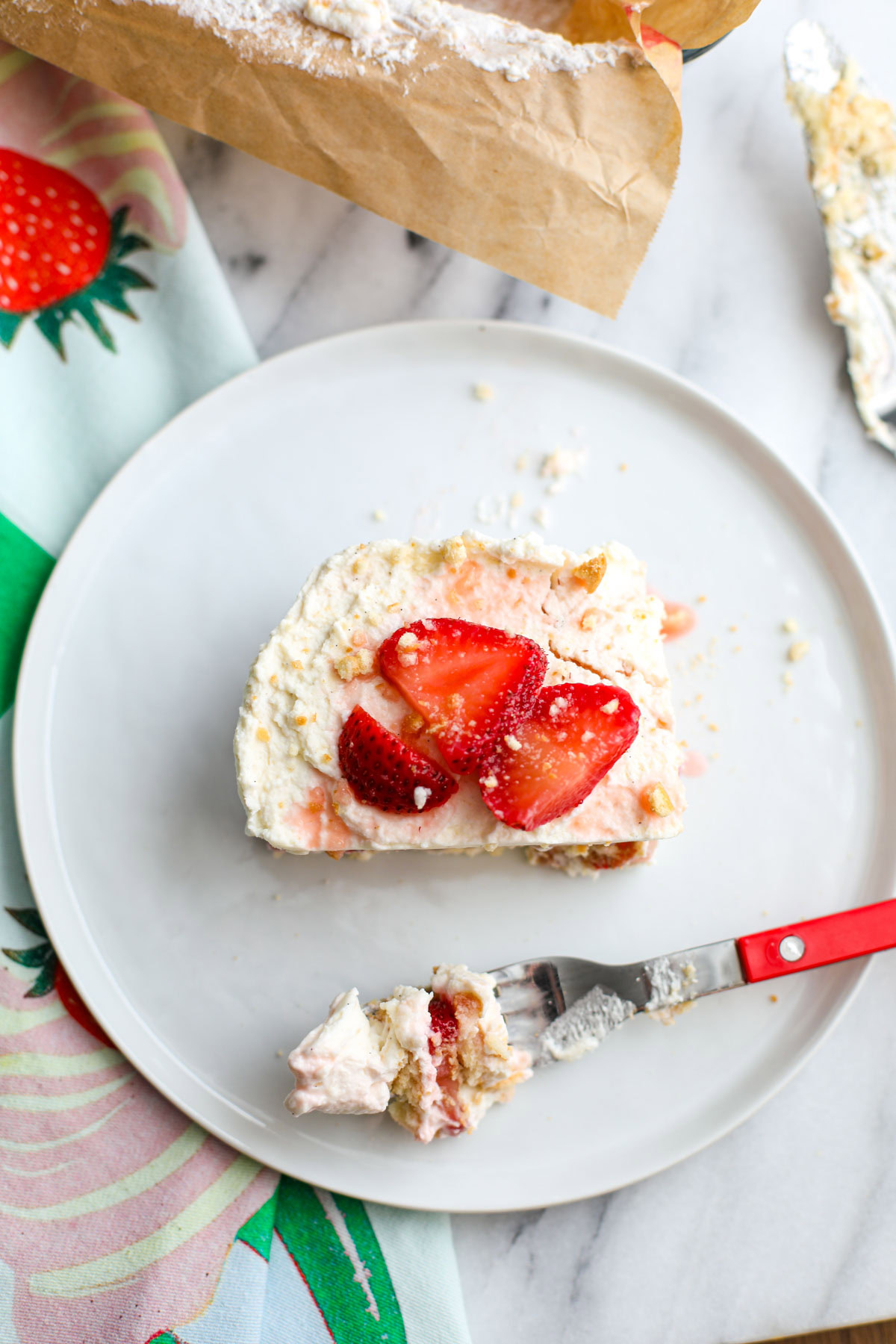 A slice of strawberry shortcake icebox cake topped with strawberries and wafer crumbs on a white plate.