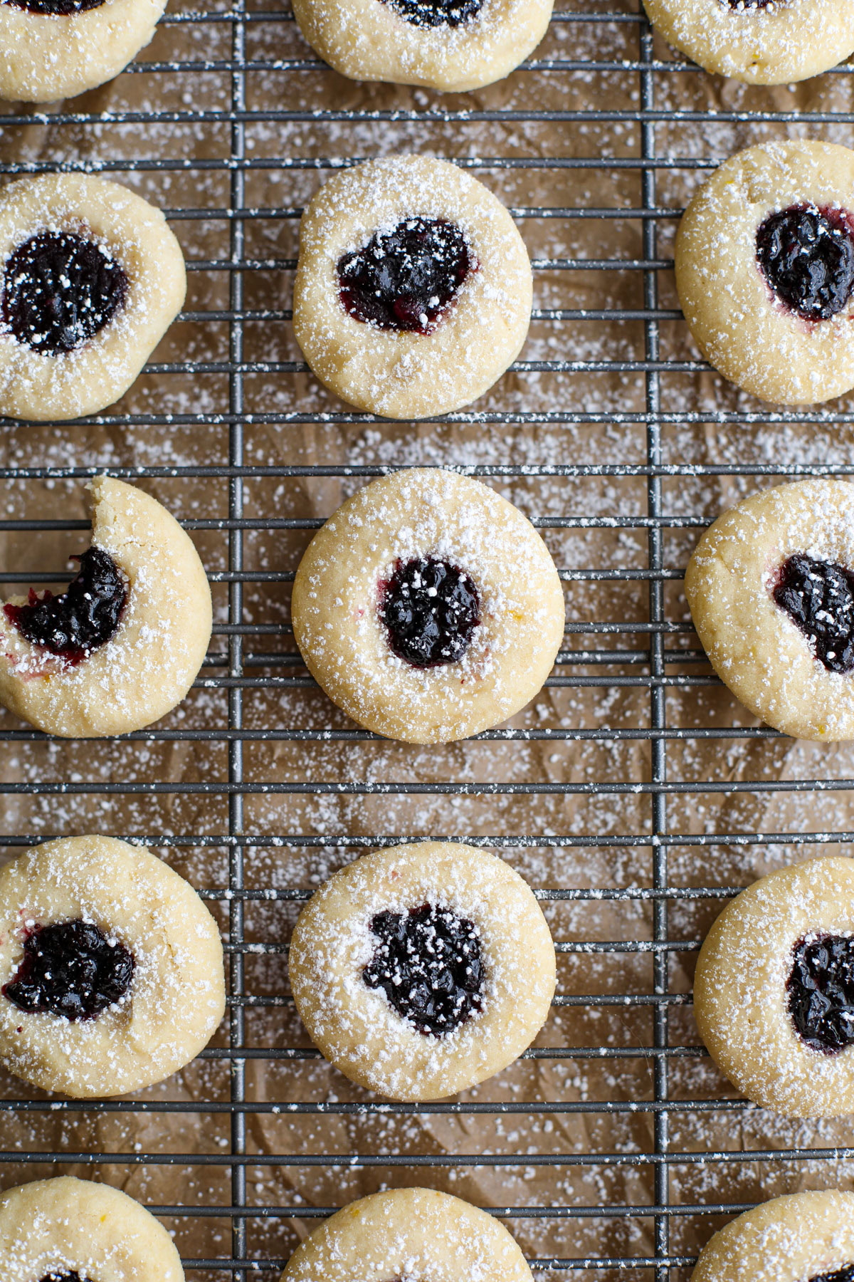 Up close of blueberry thumbprint cookies on a cooling rack and cookie sheet.