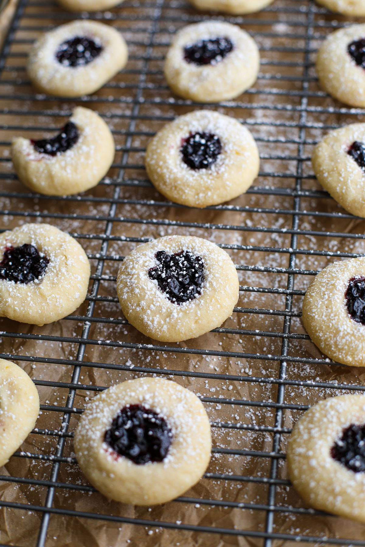 Blueberry thumbprint cookies on a cooling rack and cookie sheet.