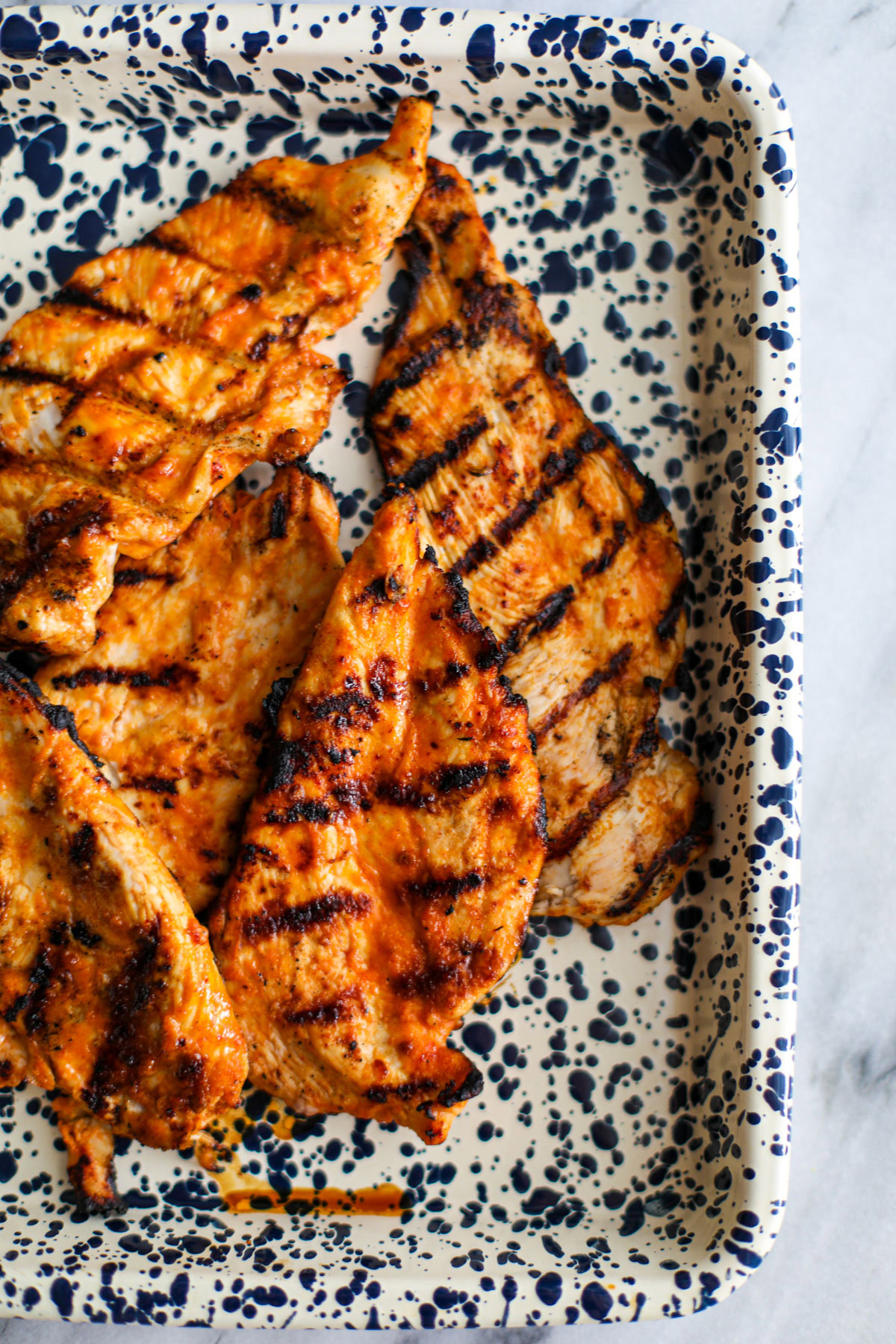 Grilled chicken with chipotle chicken marinade on a spotted tray.