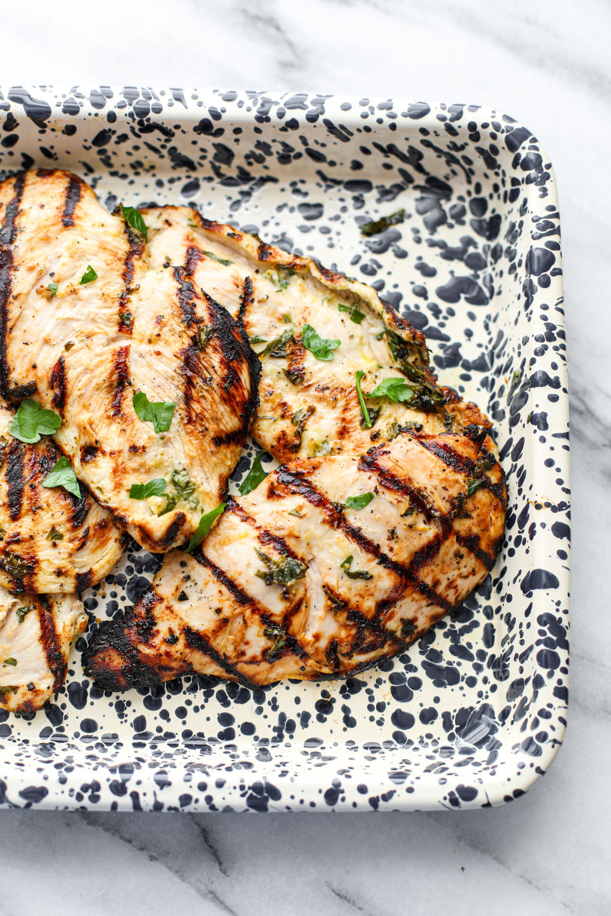 Herby grilled chicken marinade on a spotted platter.