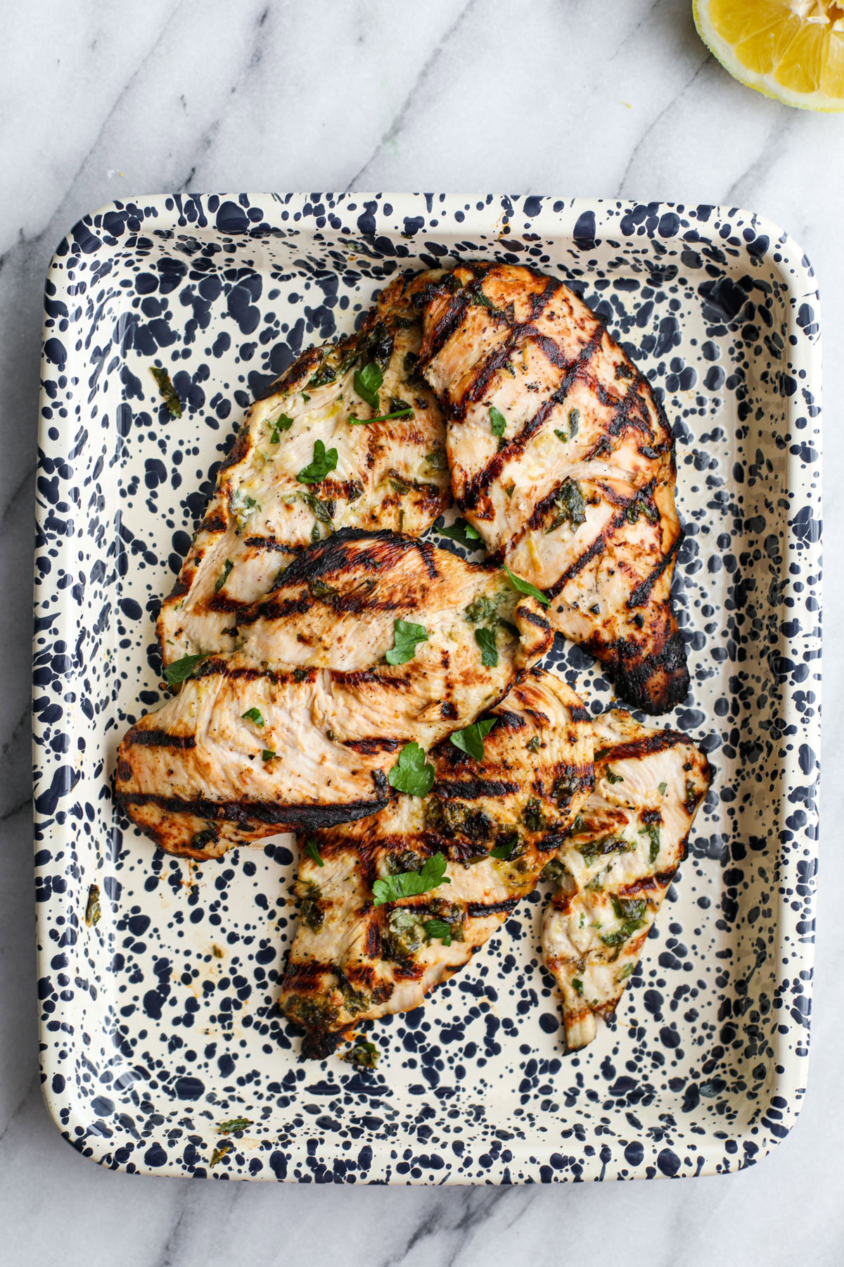 Herby grilled chicken marinade on a spotted platter.