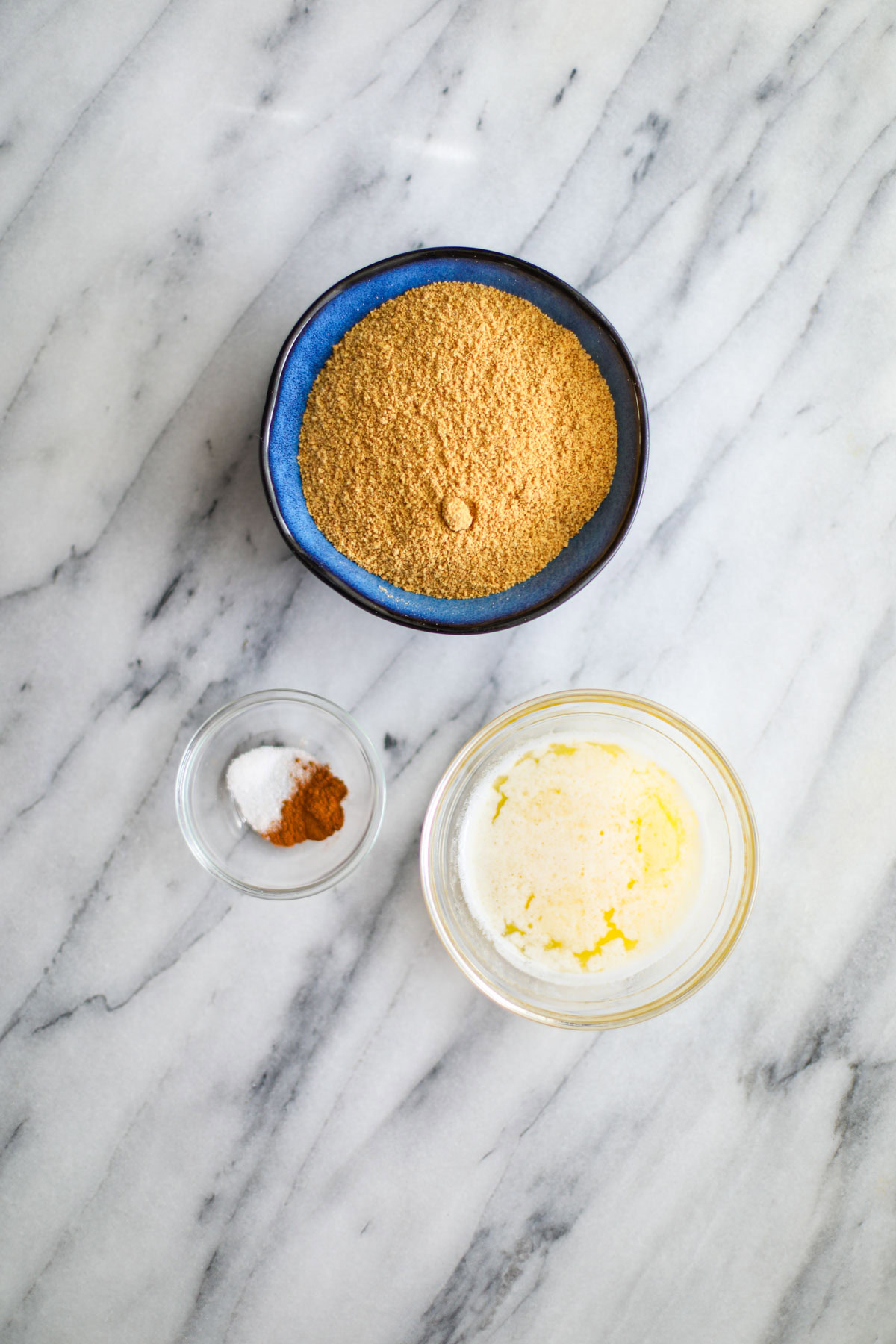 Bowls of graham cracker crumbs, butter, salt and cinnamon to make the crust.