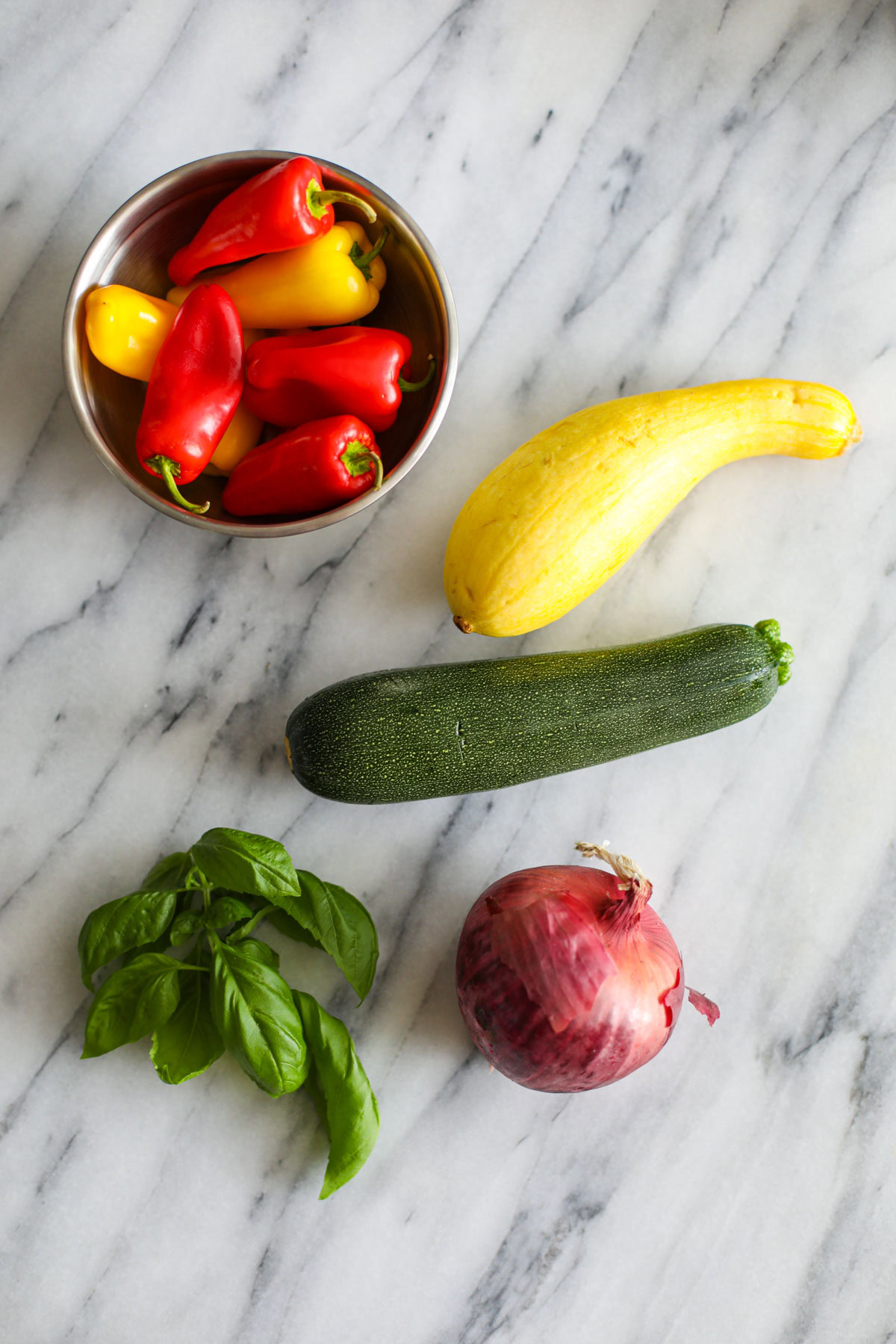 Vegetables ingredients for balsamic grilled vegetables with burrata on a white counter top.
