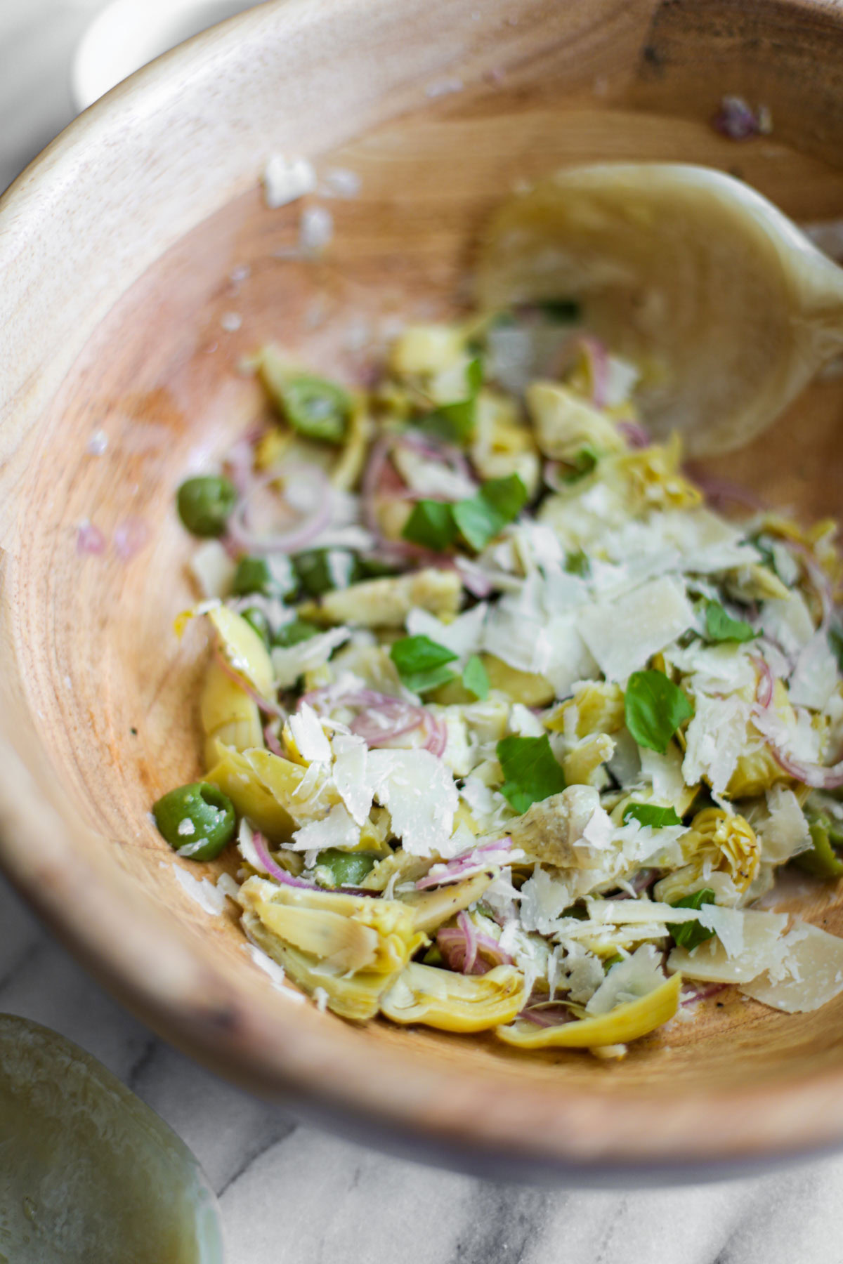 Artichoke Salad in a wood bowl with a serving spoon.