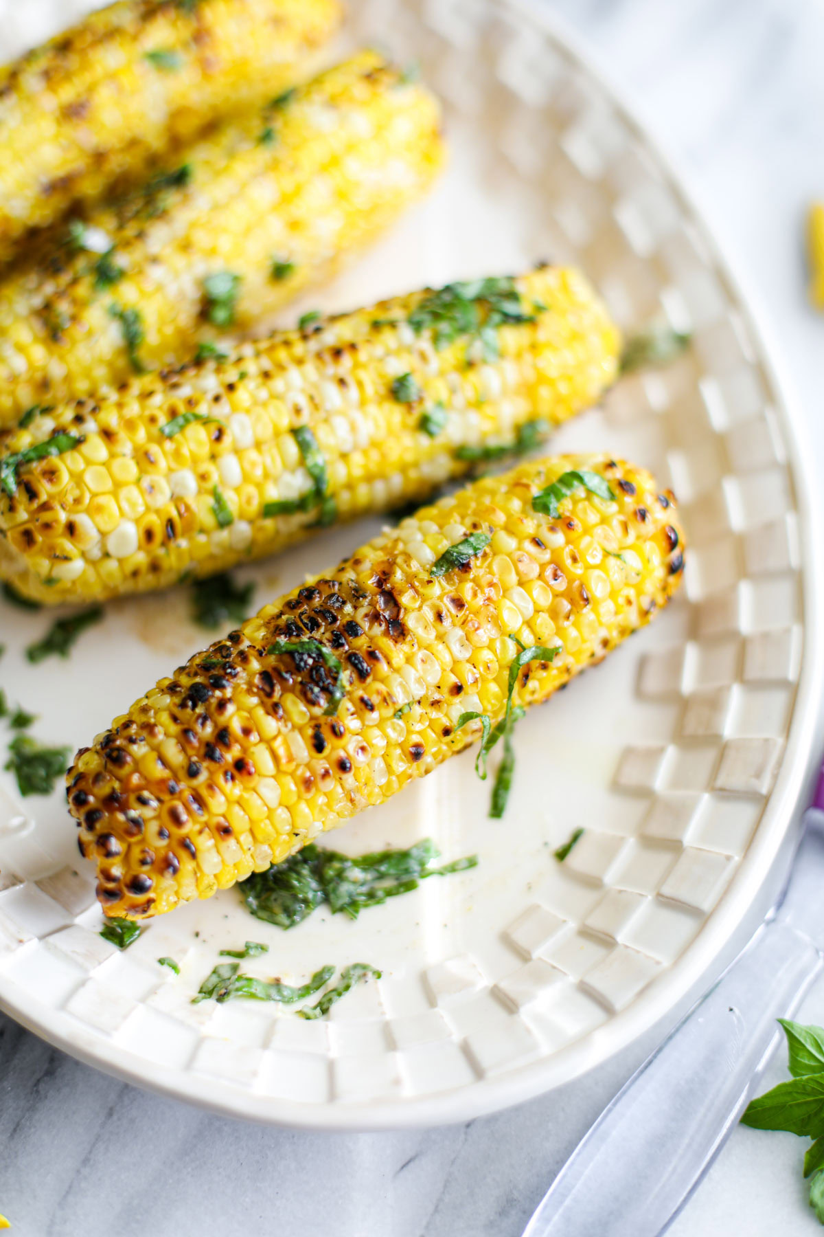 A piece of charred corn with basil and butter.