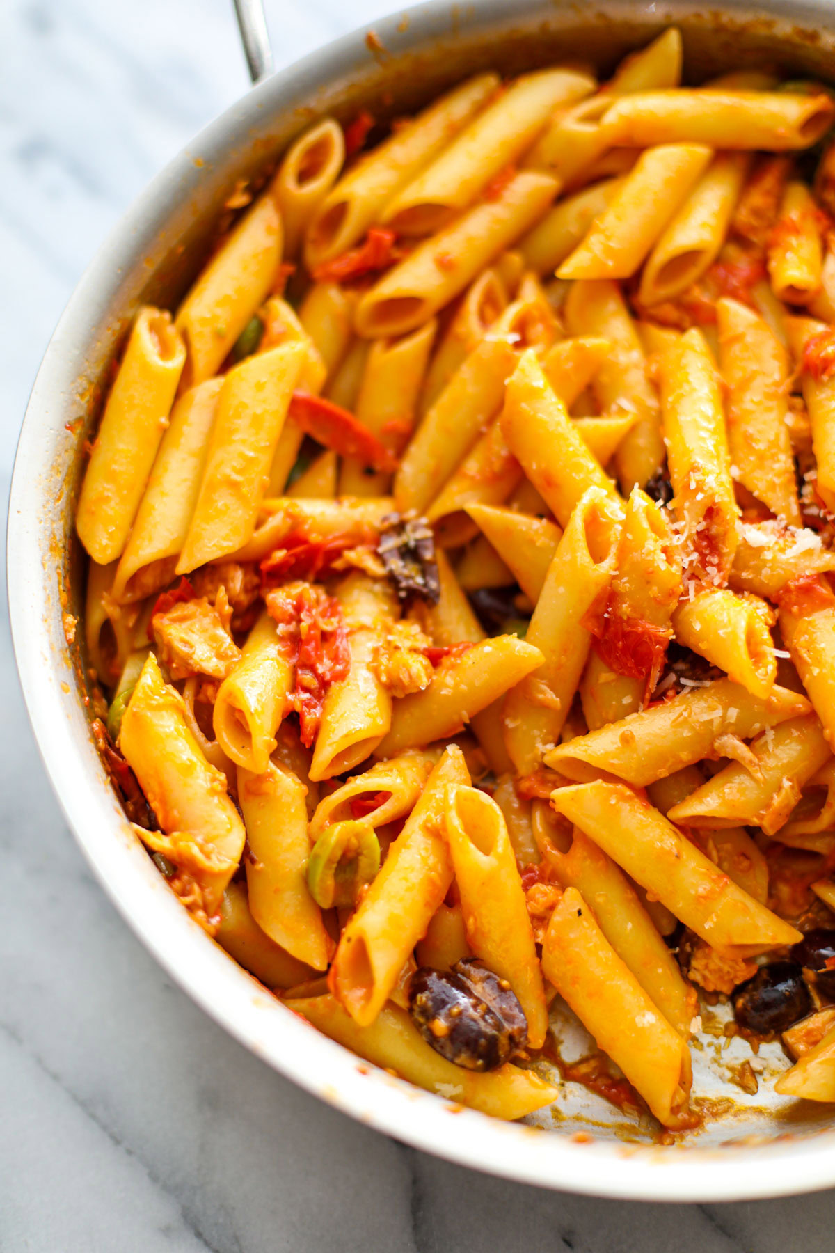 Up close of canned tuna pasta in a stainless skillet with a wooden spoon.