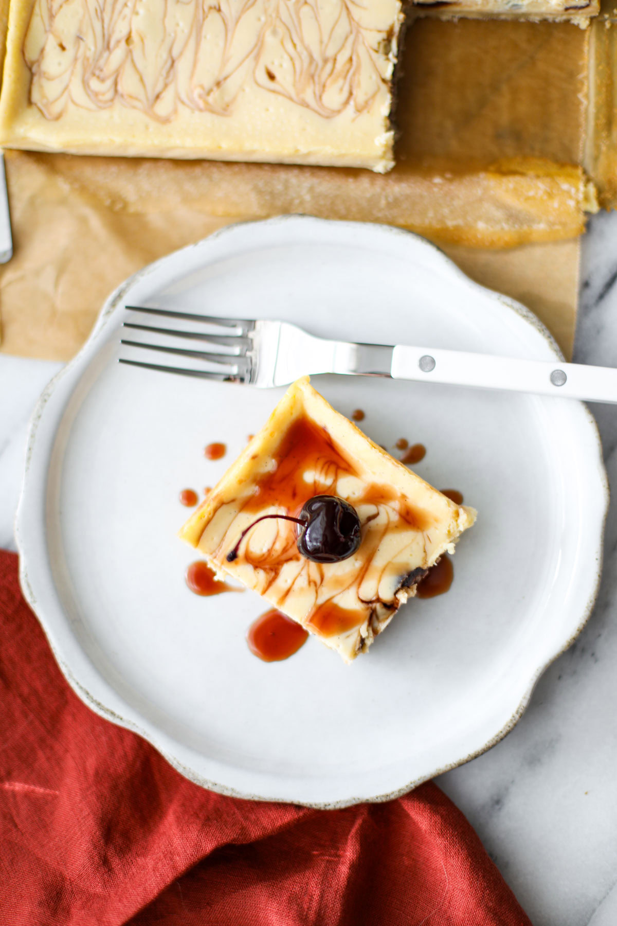 An amarena cherry cheesecake bar on a white plate with a white fork.