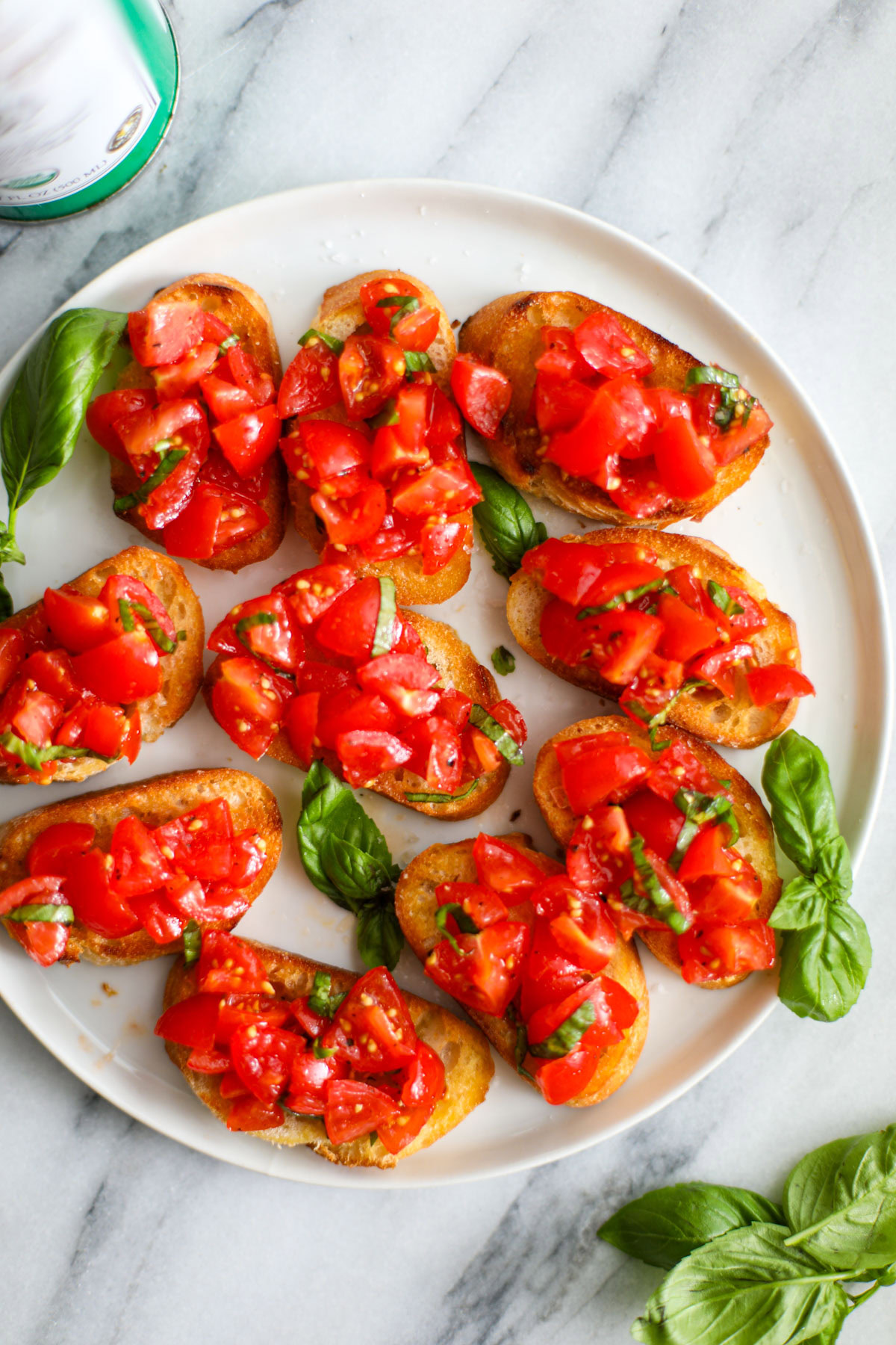 Cherry tomato bruschetta on a white plate garnished with basil.