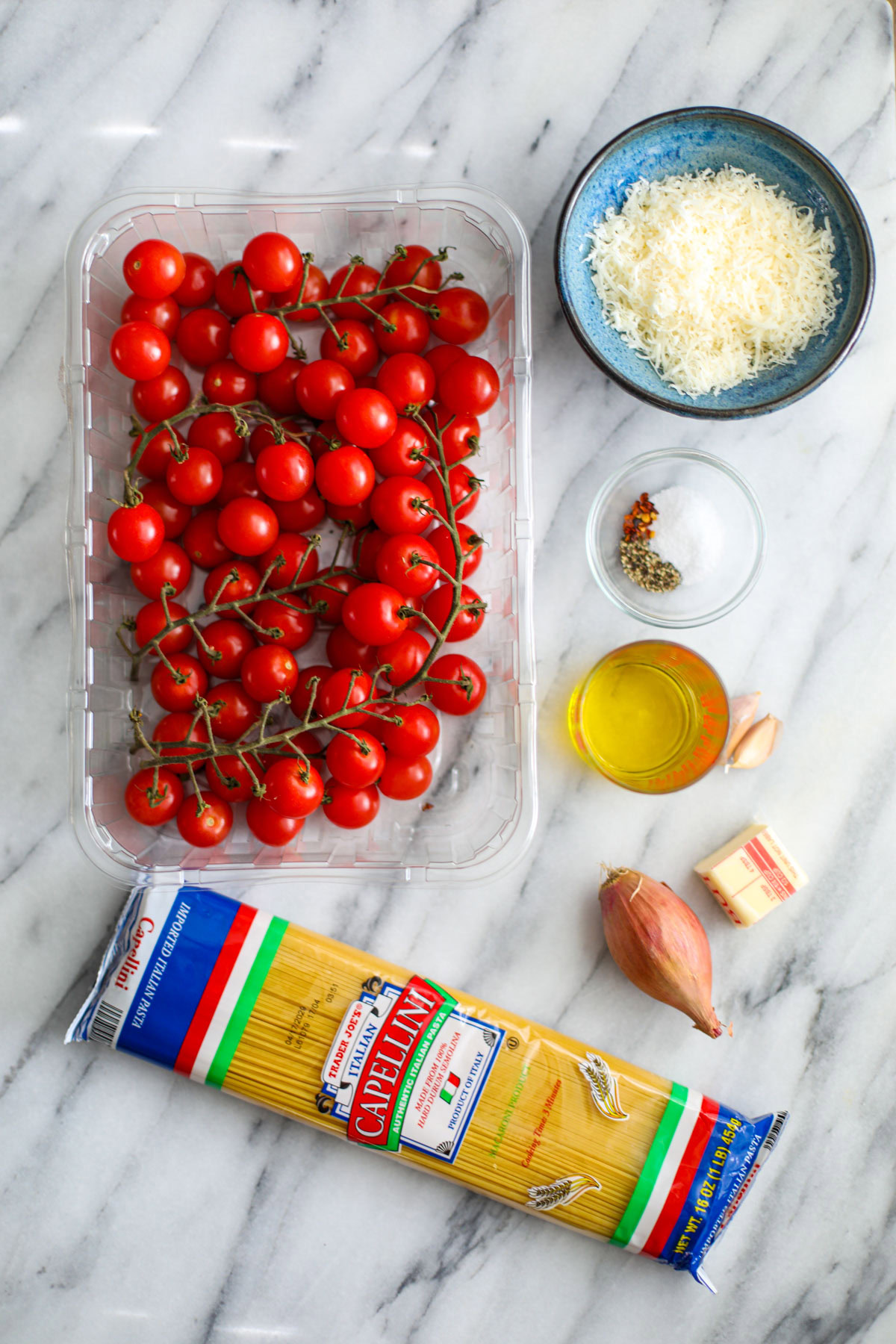 a large container of cherry tomatoes, bag of pasta, shallot, butter, oil, garlic, and grated cheese.