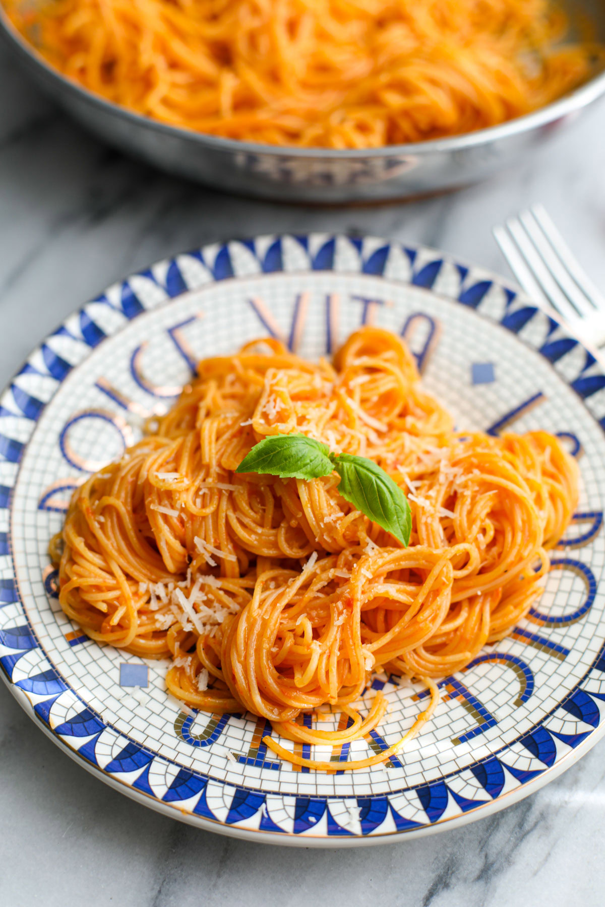 Cherry tomato pasta sauce coated spaghetti on a blue and white plate.