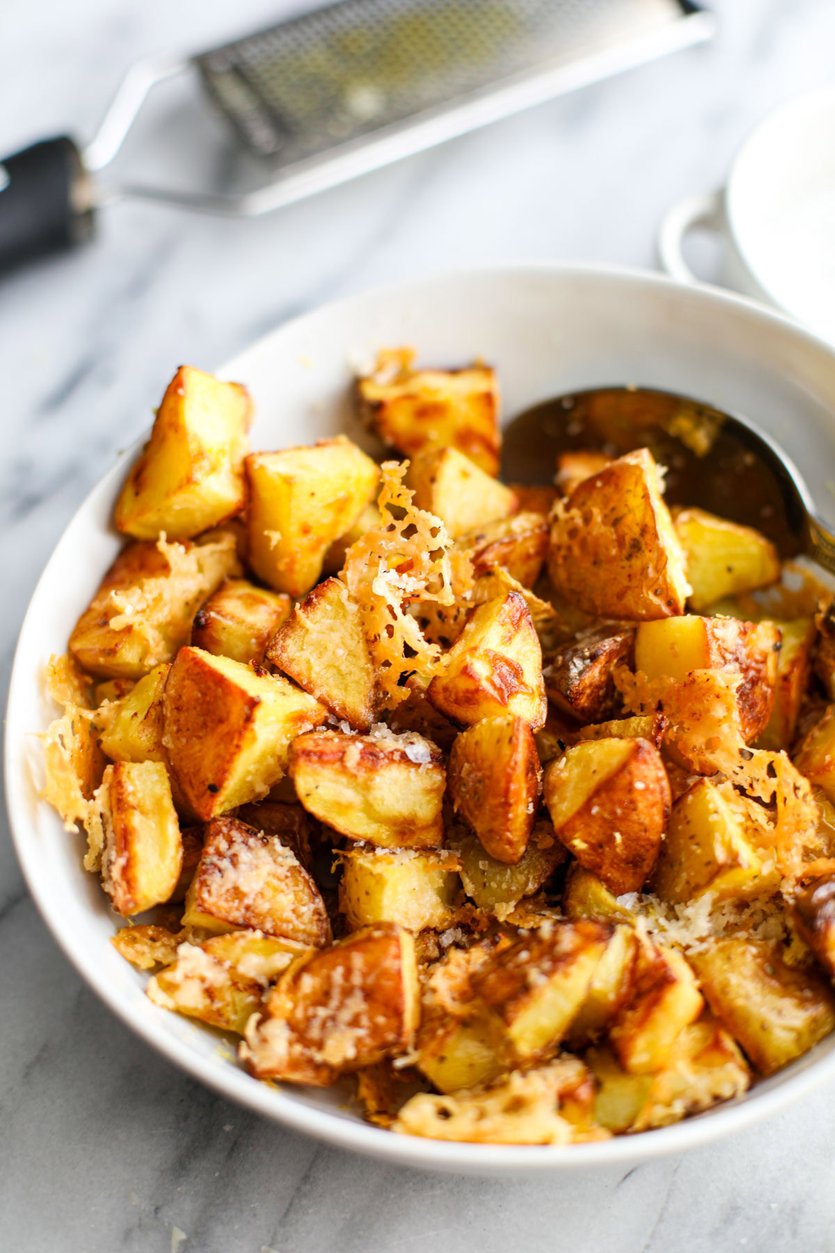 A white bowl of crispy parmesan potatoes.