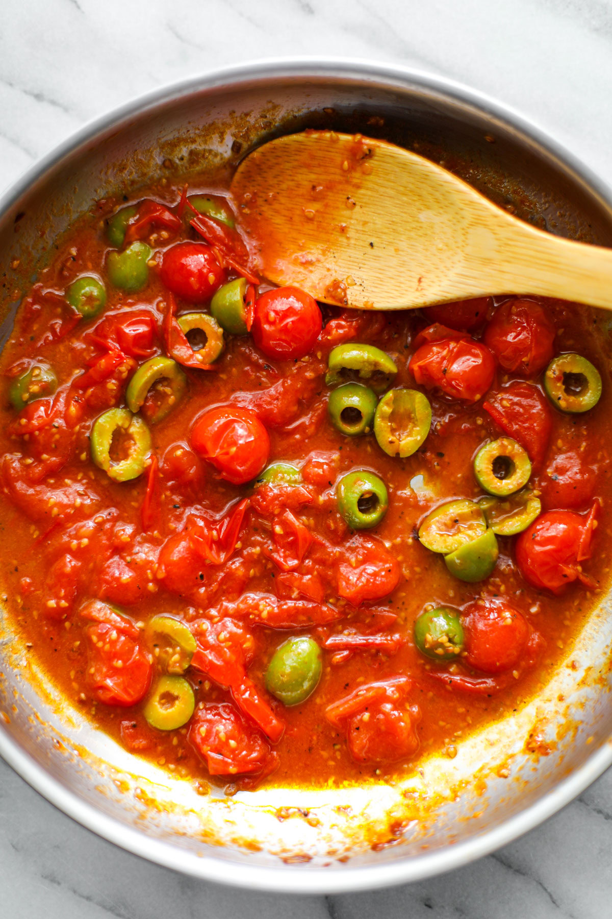 Jammy tomatoes in a stainless steel skillet.