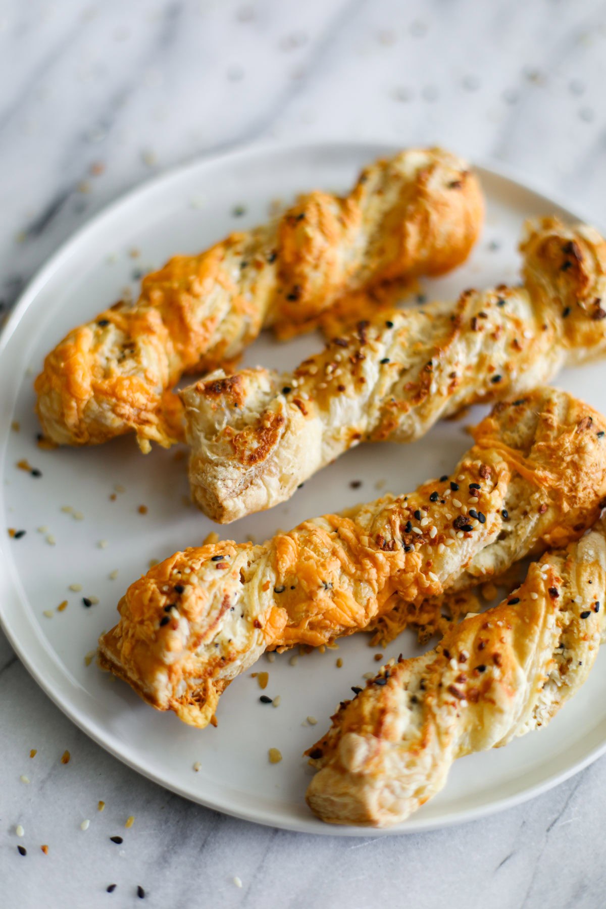 Everything bagel puff pastry twists on a white plate. 