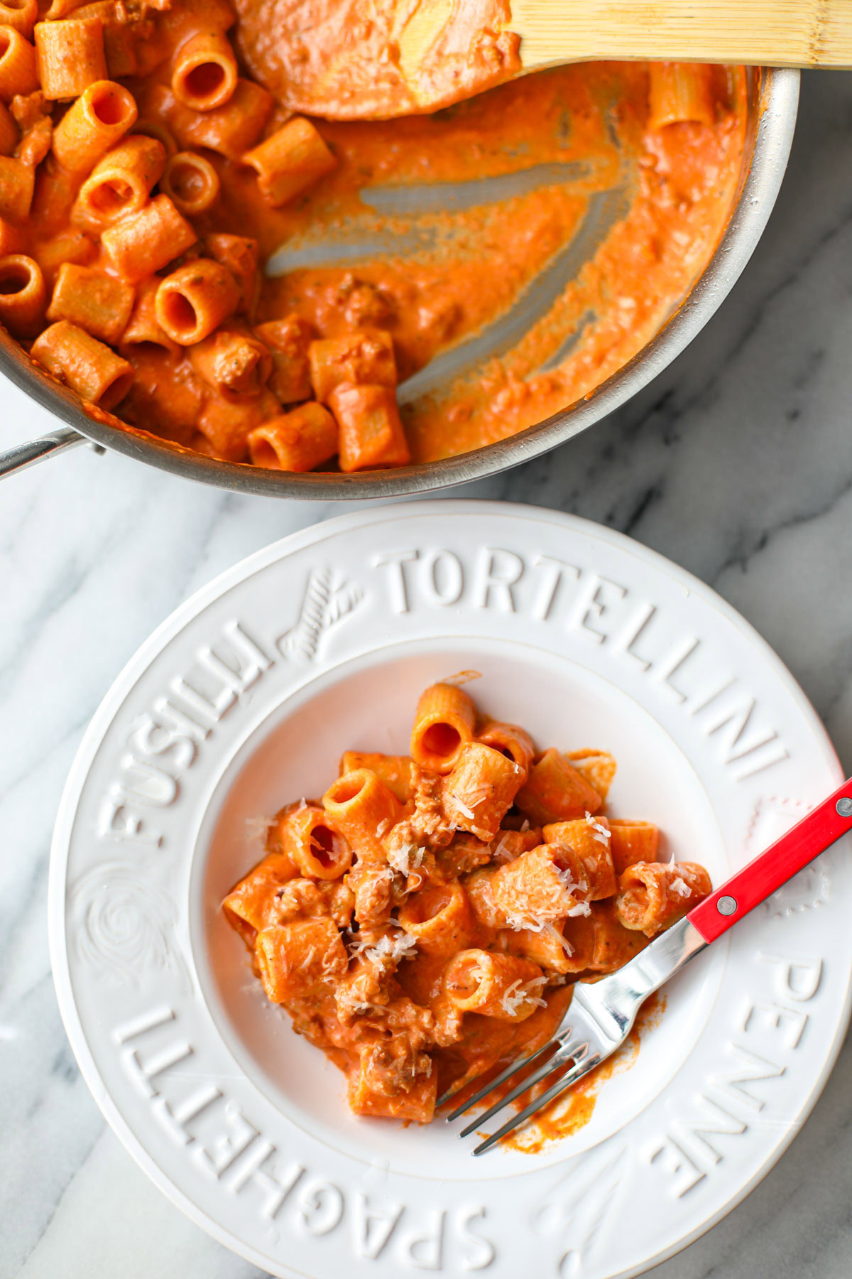 A white bowl of creamy sausage rigatoni.