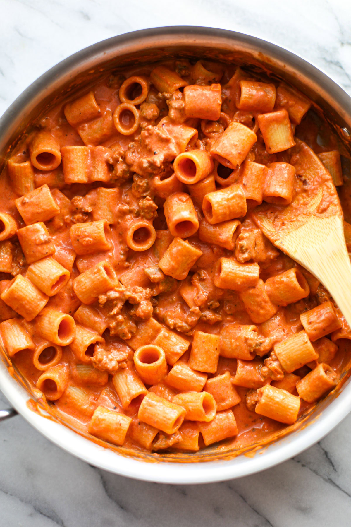 A stainless steel skillet of creamy sausage rigatoni.
