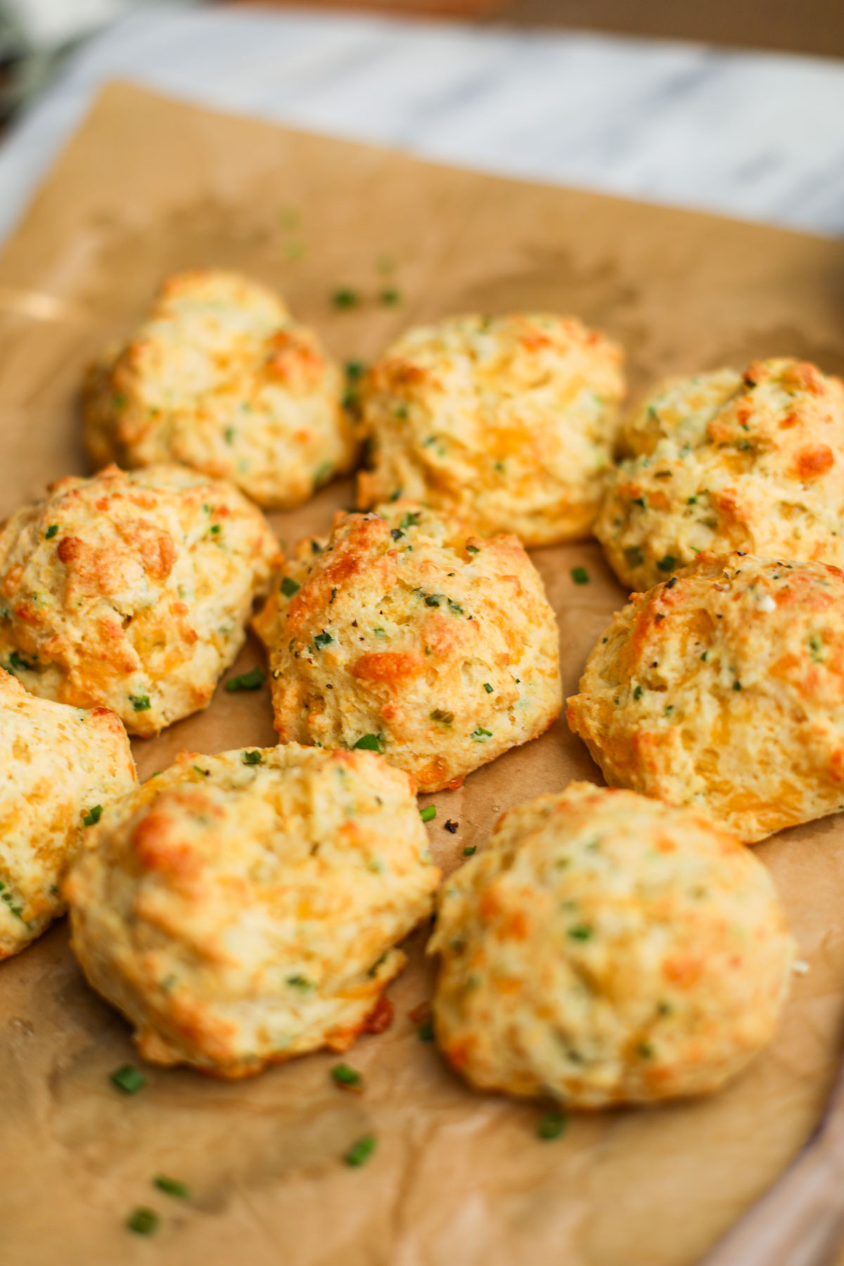 Up close of a cheddar chive biscuit with crispy edges and dotted with chives.