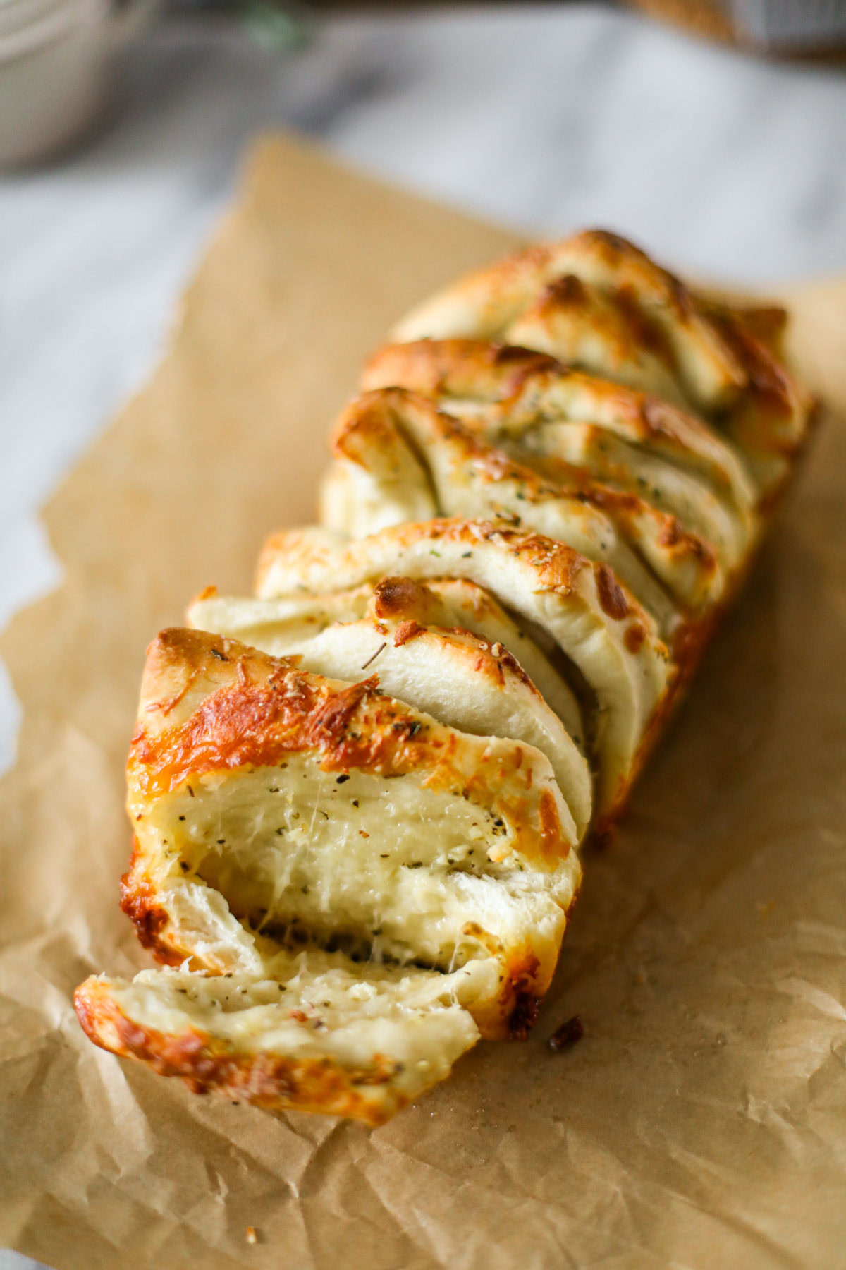 Golden garlic pull apart bread in a loaf pan with melted mozzarella and Parmigiano Reggiano between the layers